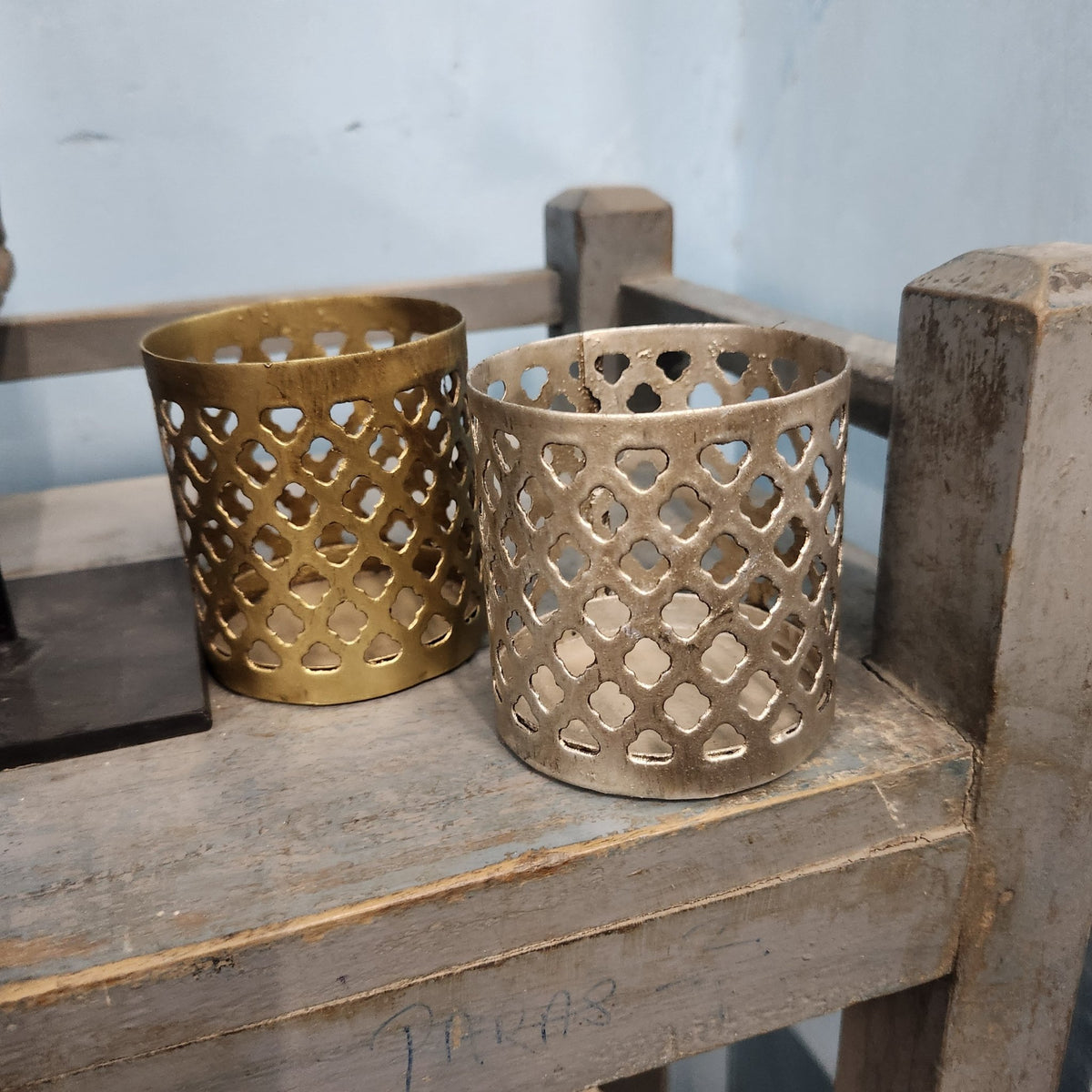 Iron tea light holders with fret-work sides, painted in silver and gold, 9cm high and 9cm in diameter.
