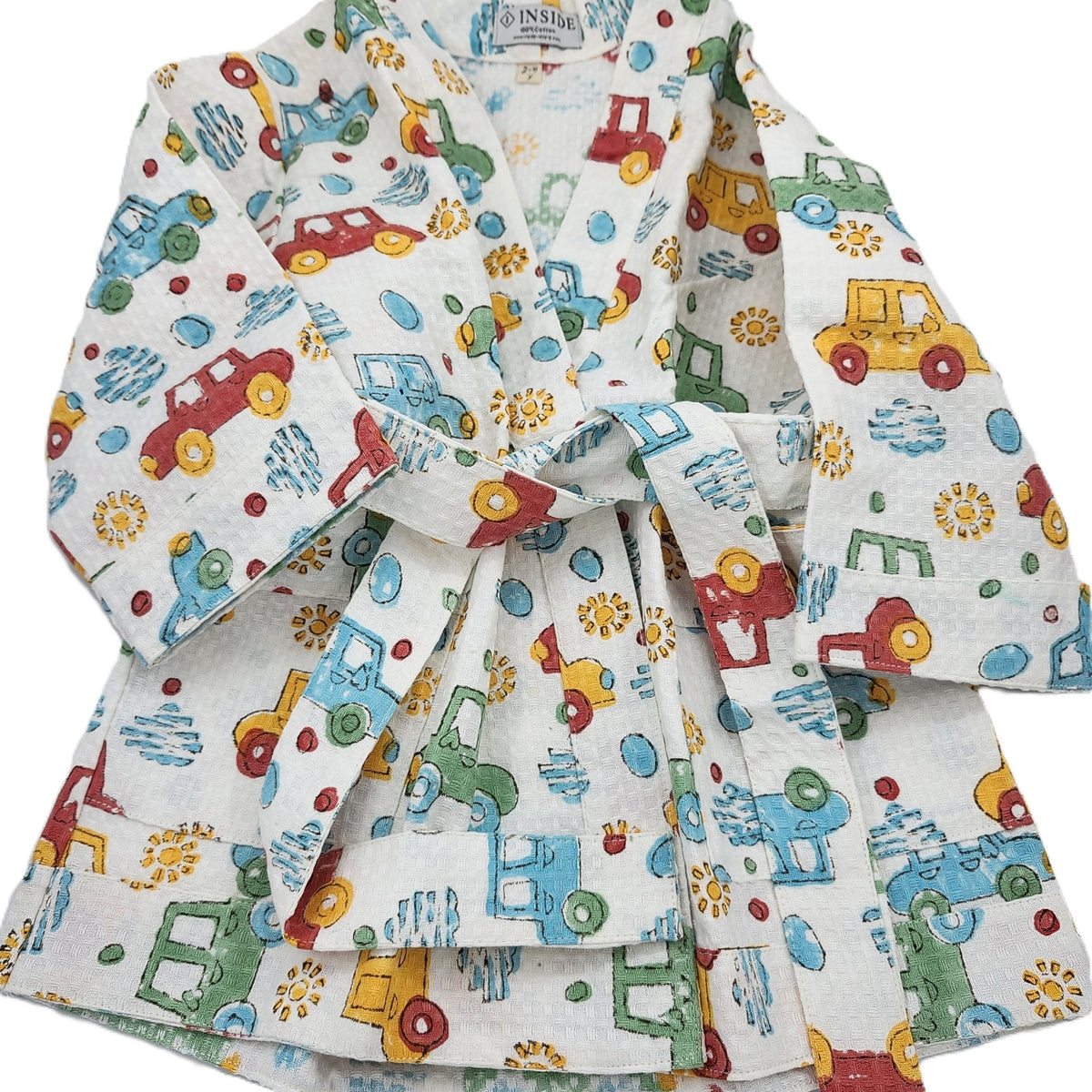 Short child's bath robe in block printed cotton waffle, covered in cars in red, blue, green and yellow, sizes age 2 to 6