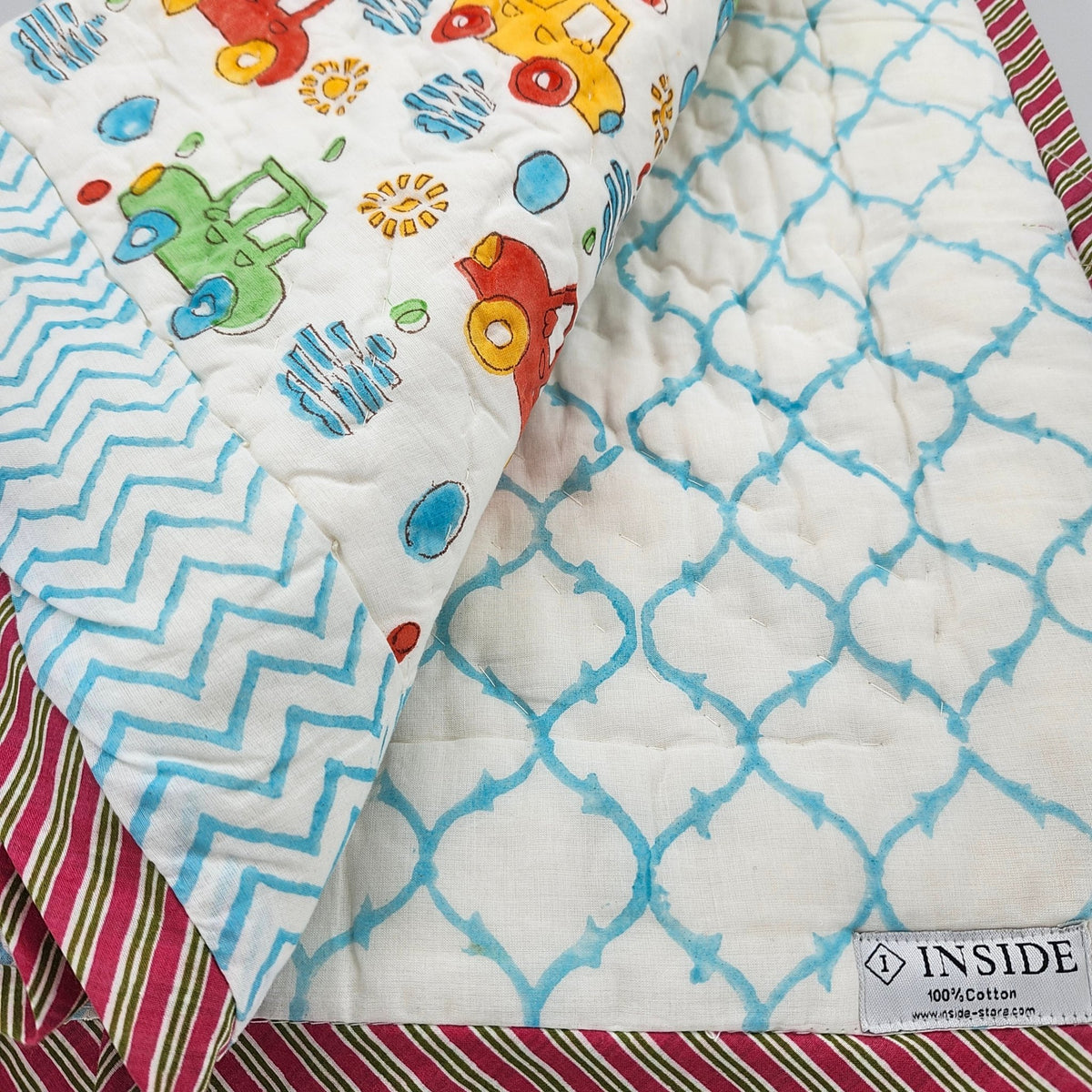 Child's block print quilt in organic cotton cambric with a colourful car design, a blue trellis on the reverse, 102 by 152cm