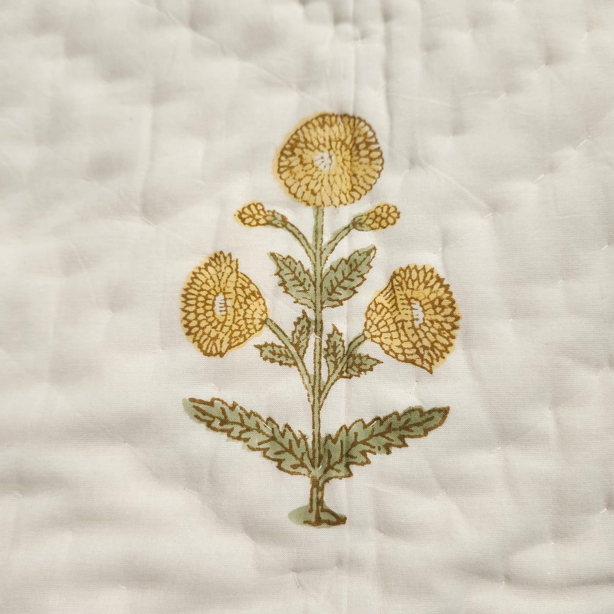 Child's block print quilt in fine organic cotton cambric, a large yellow marigold print on one side, 102 by 152cm in size