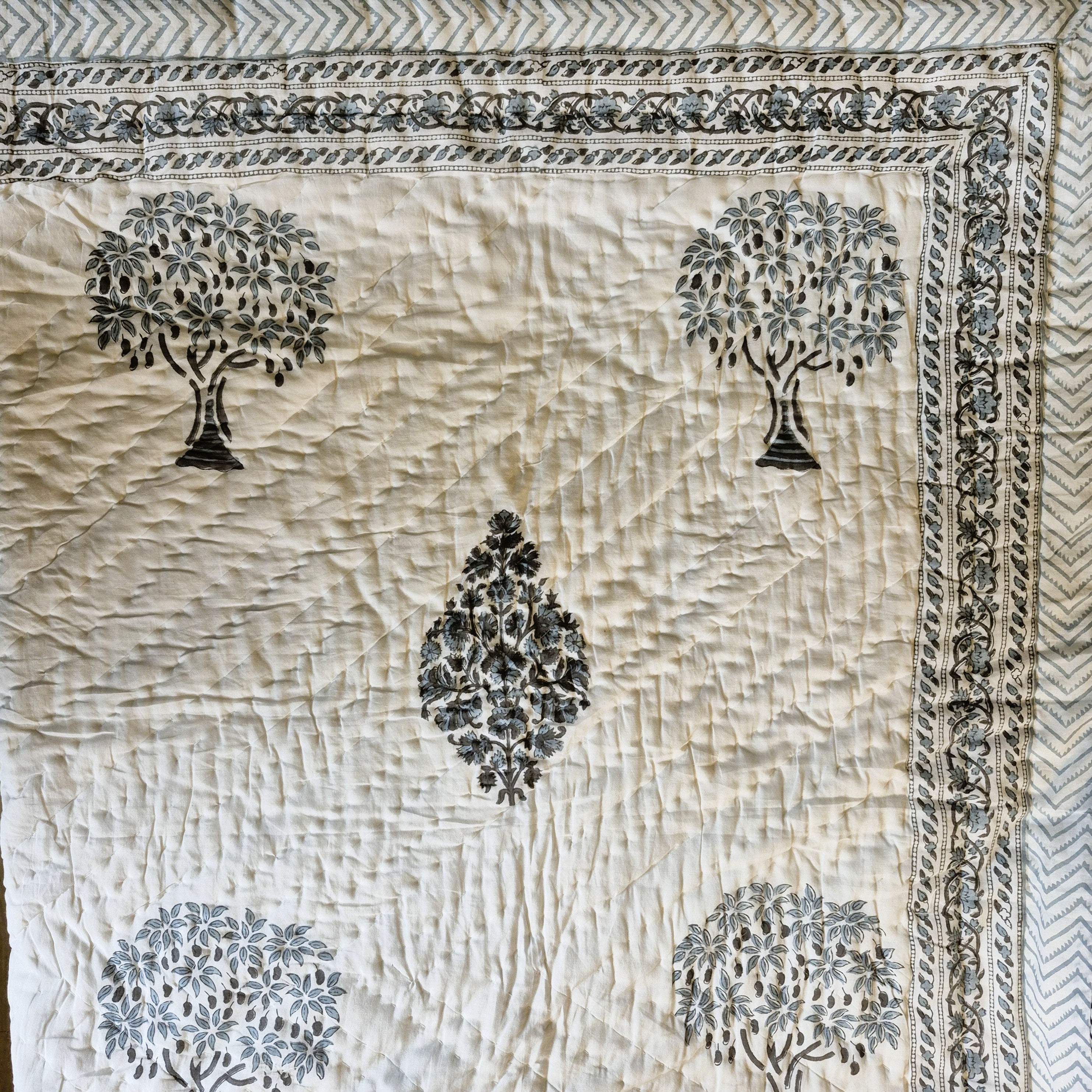 Single block-print quilt with a mango tree print and blue striped border