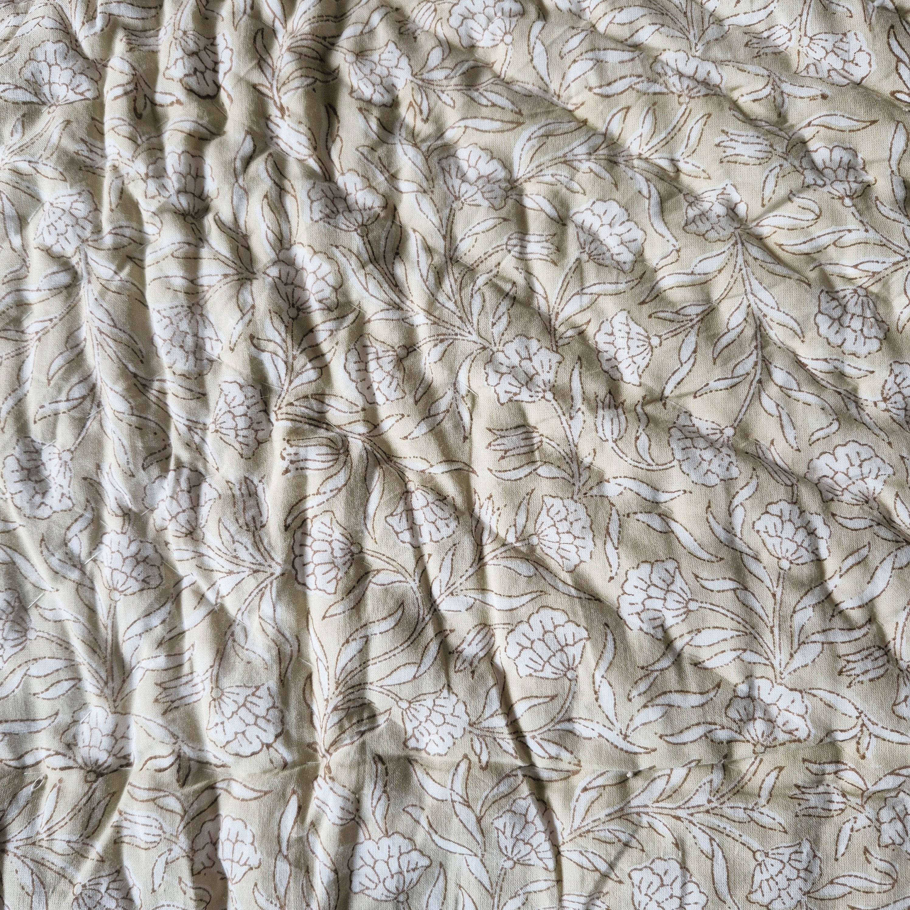 Toddler block-print cotton quilt with beige and white stripes and a white-on-beige floral reverse