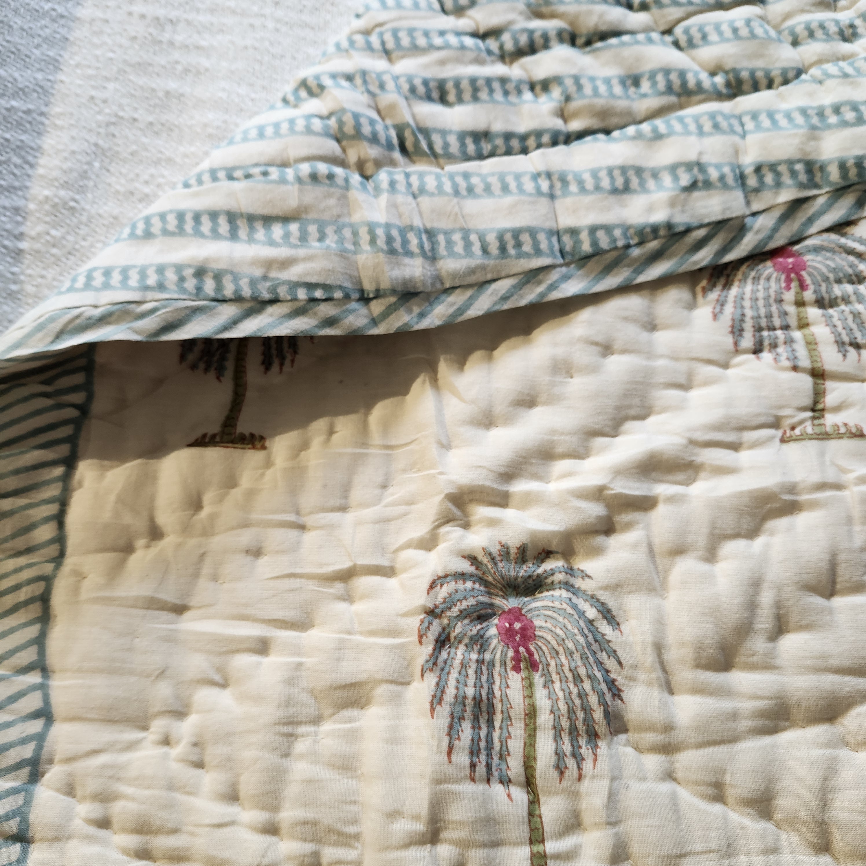 Children's block-print cotton quilt with a pattern and contrast striped reverse