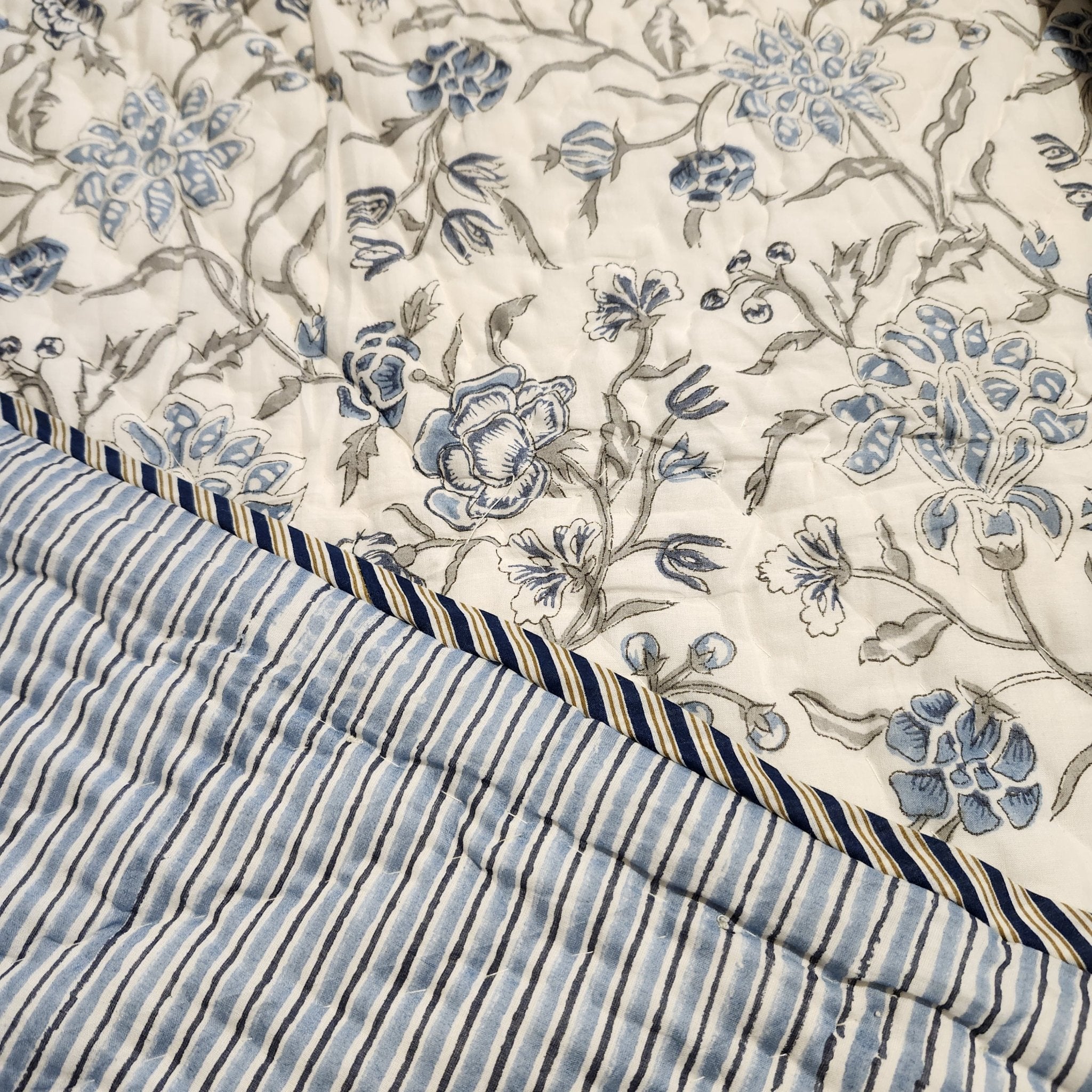 Single block-print quilt in a blue floral pattern with striped reverse