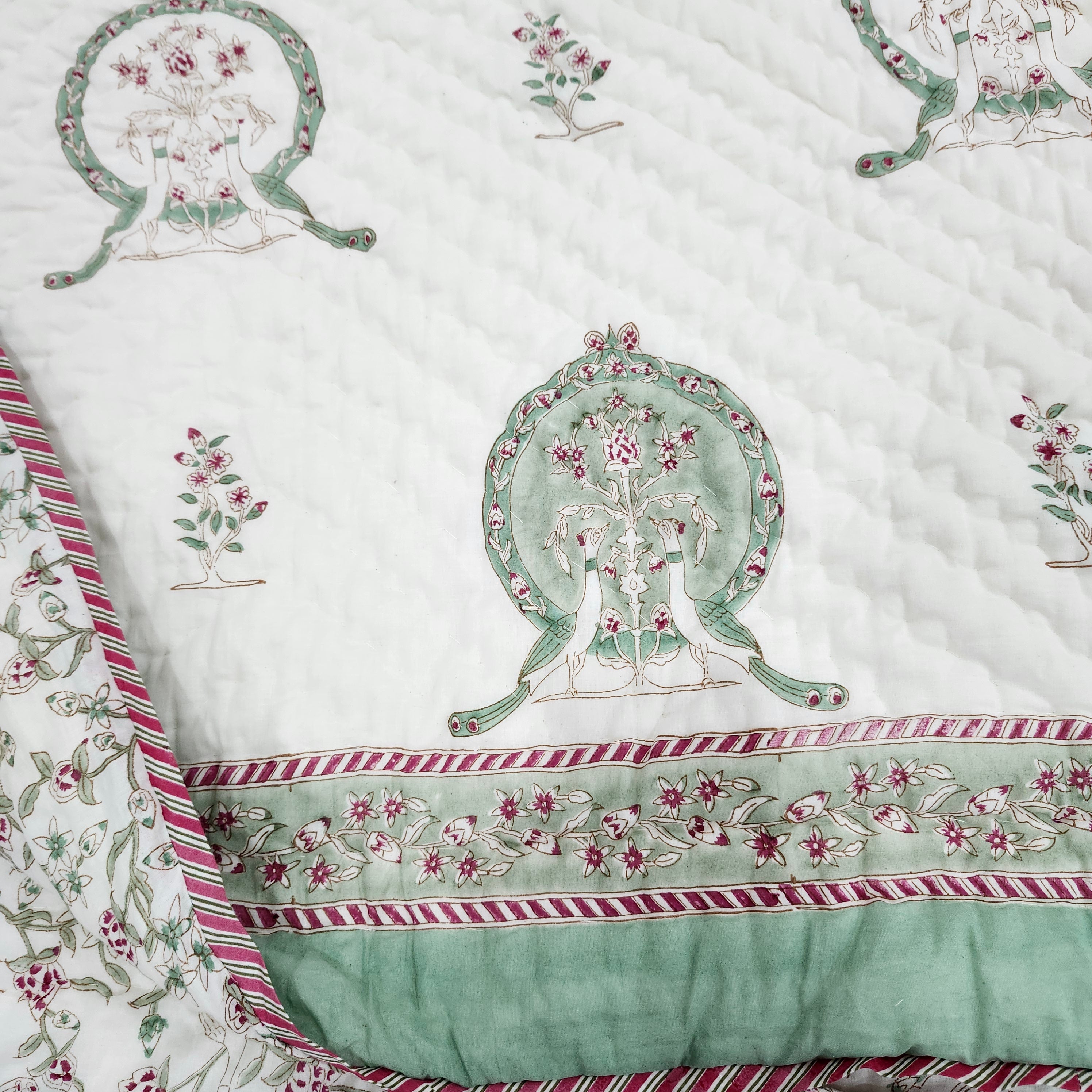 Single block-print quilt with peacocks and a floral reverse, styled on a bed