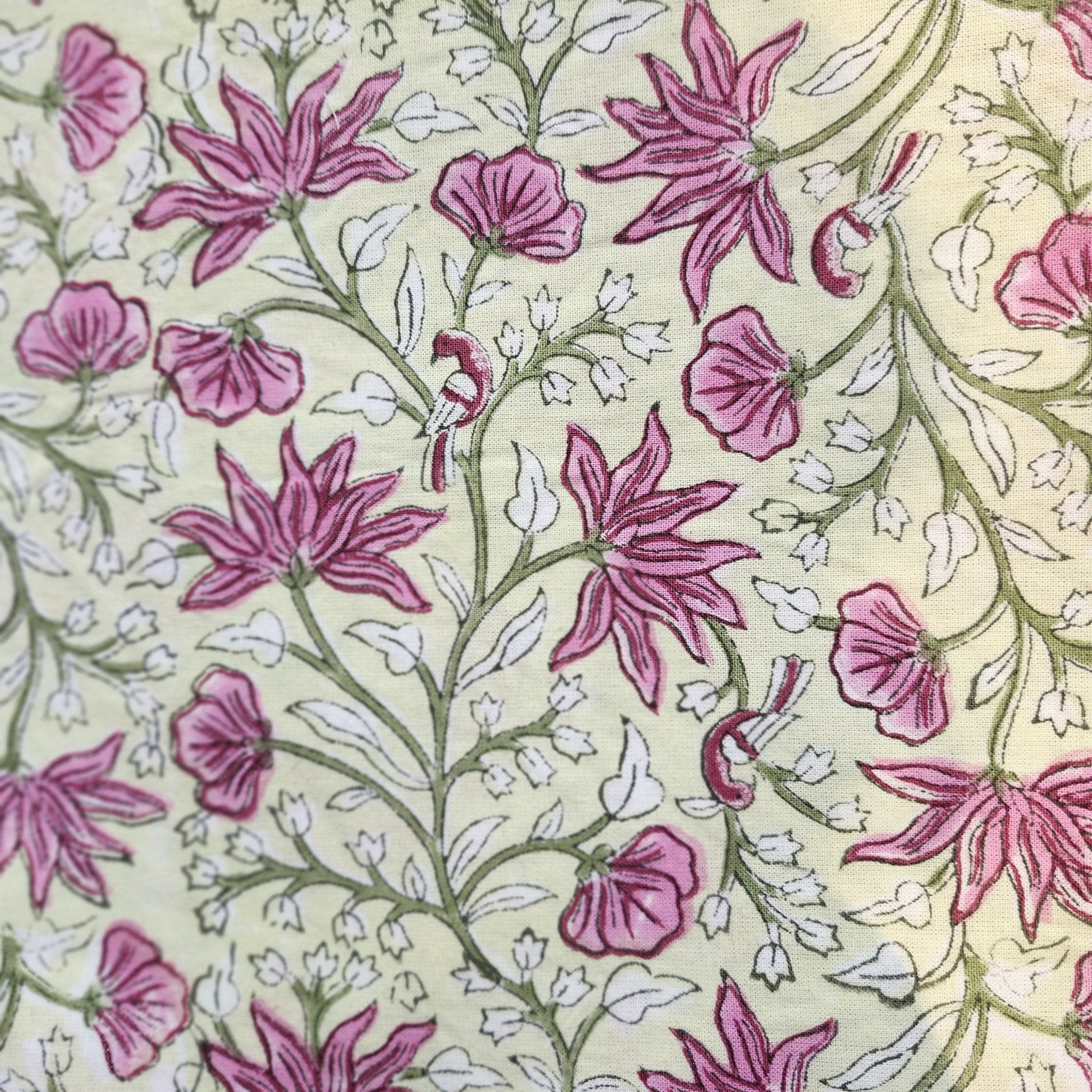 Floral block print table cloth with pink flowers, green leaves and tiny birds on a pale yellow background