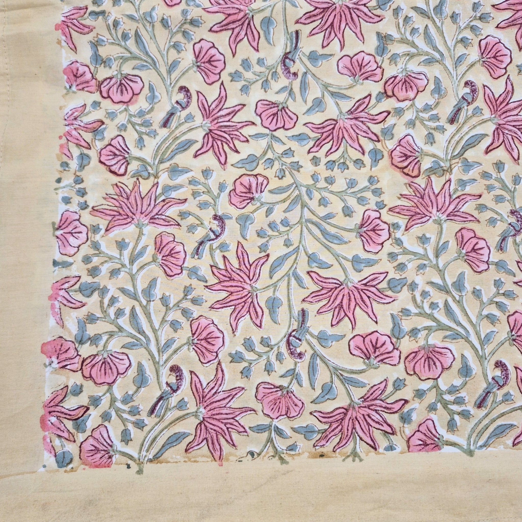 Floral block print table cloth with pink flowers and little birds on a mustard background