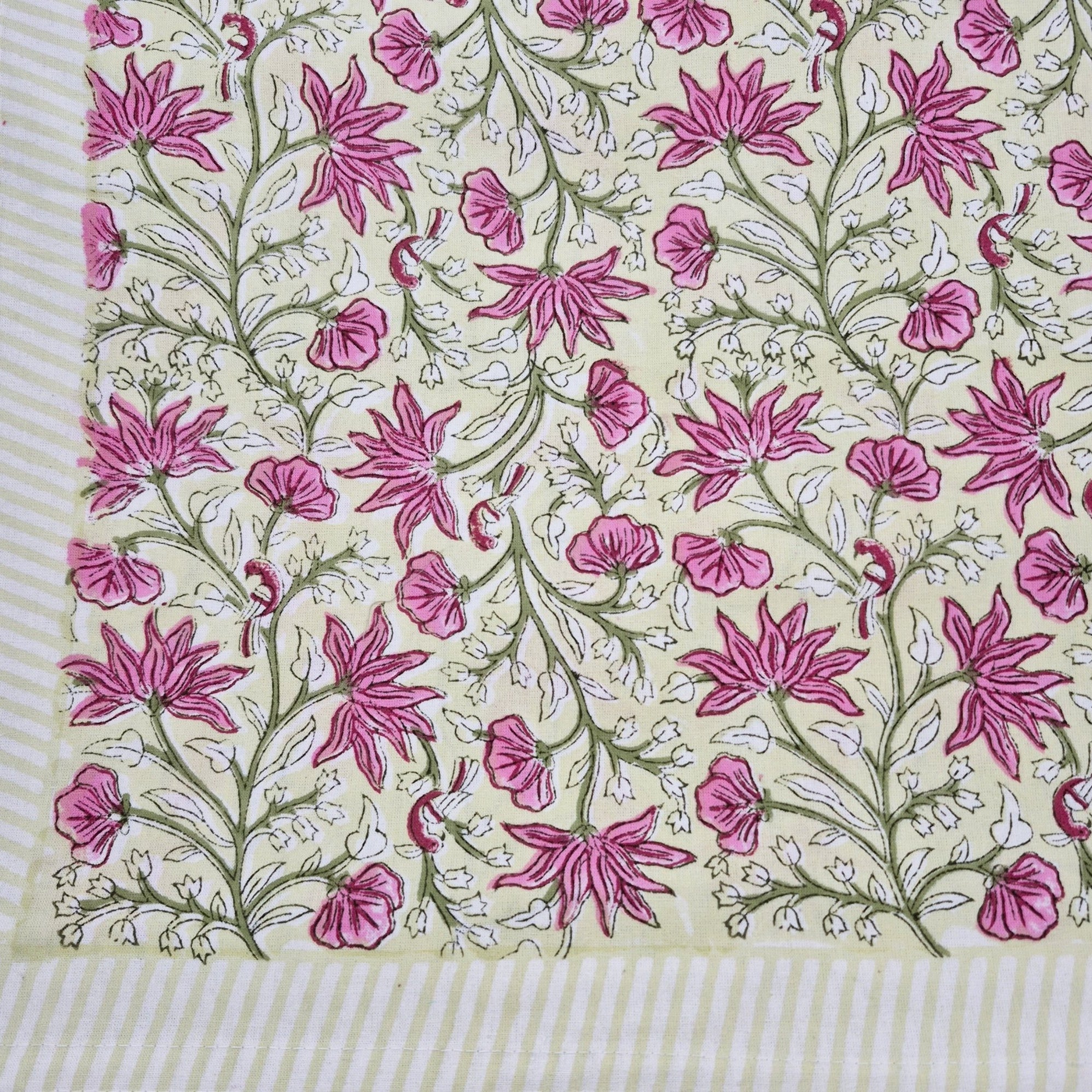 Floral block print table cloth with pink flowers, green leaves and tiny birds on a yellow background
