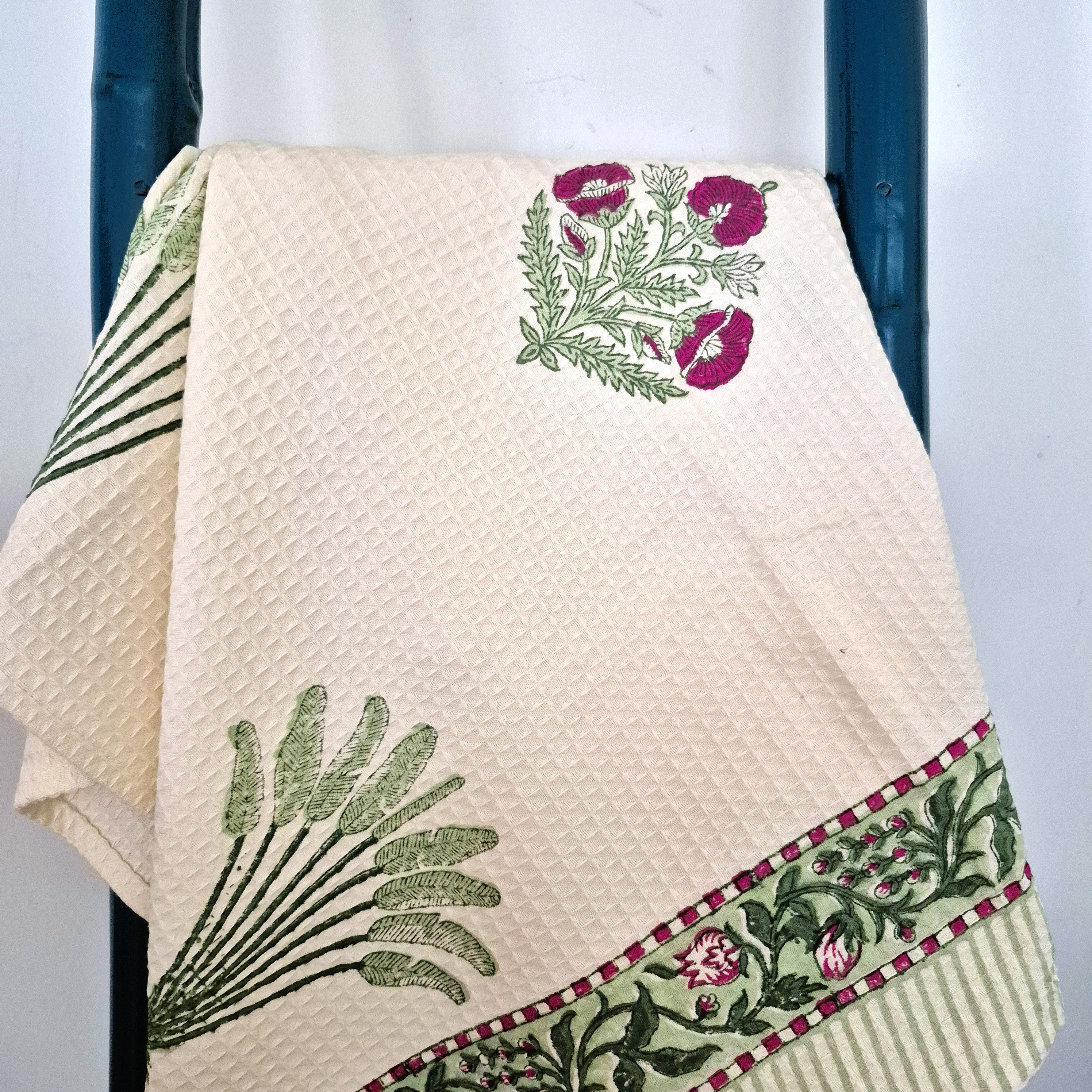 Cream waffle towel with floral and palm patterns hanging on a towel ladder