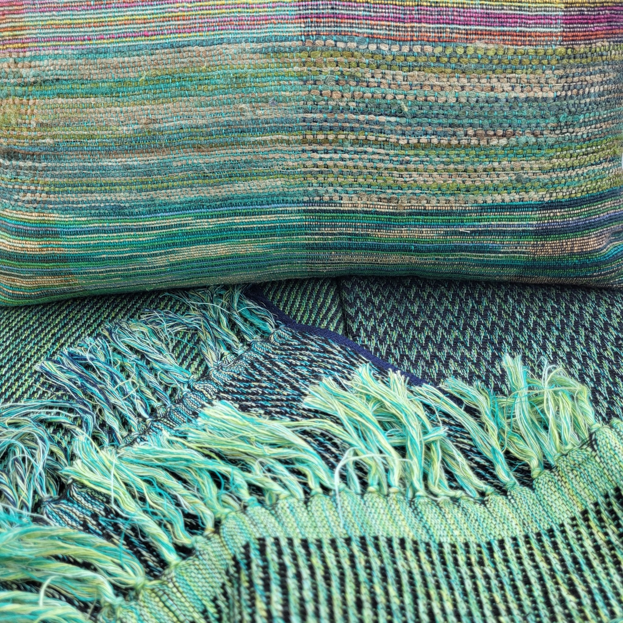 Rainbow handwoven cushion styled with an emerald throw, linen and silk