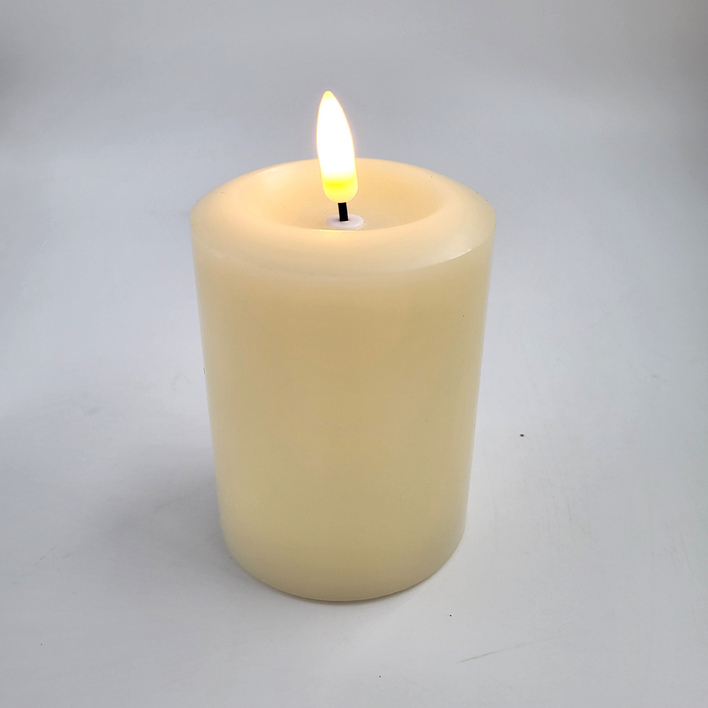 Flameless ivory pillar candle styled inside a glass hurricane lamp