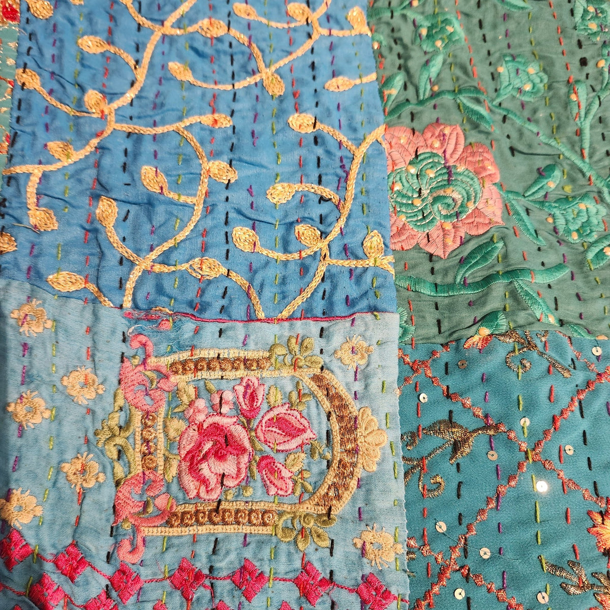 Detail of the blue floral block print patchwork and hand stitching on a kantha single quilt, also used as a tablecloth