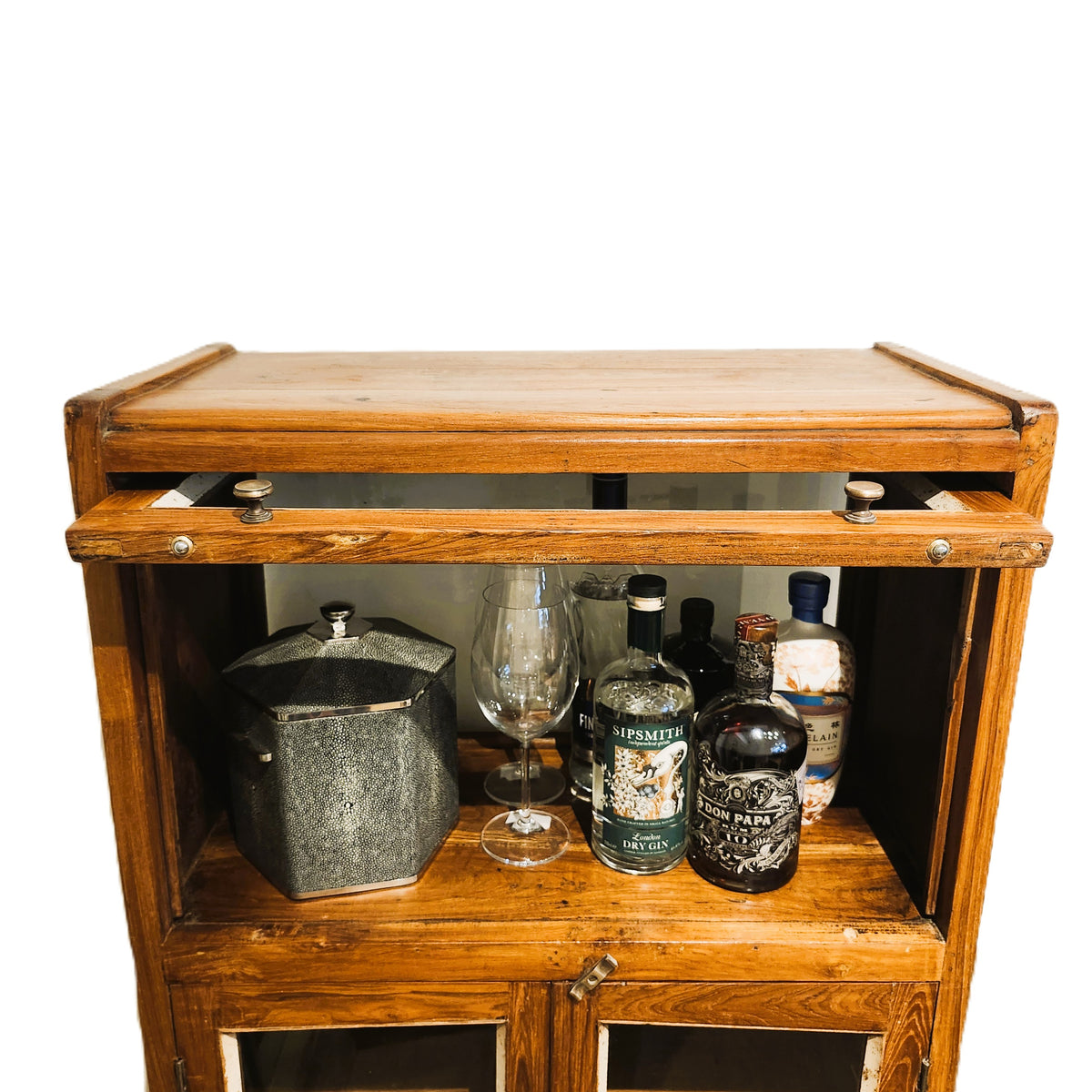 Detail of the glass fronted doors on a small vintage teak drinks cabinet in natural wax, 129cm high, 65cm wide, from India