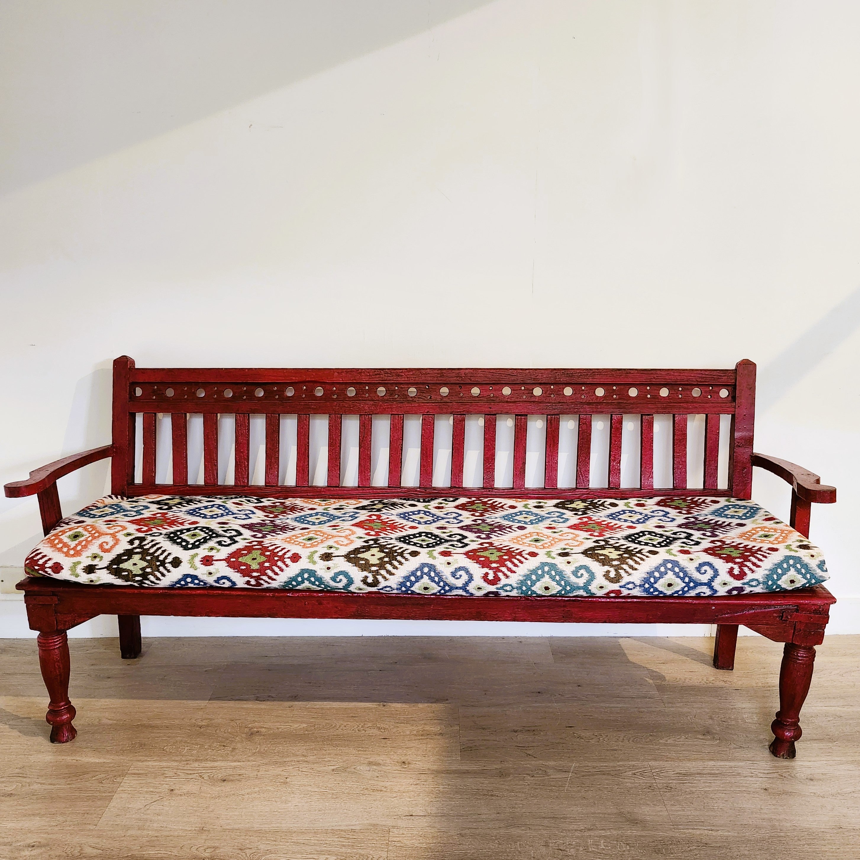 Red painted vintage teak bench, ikat seat cushion, styled