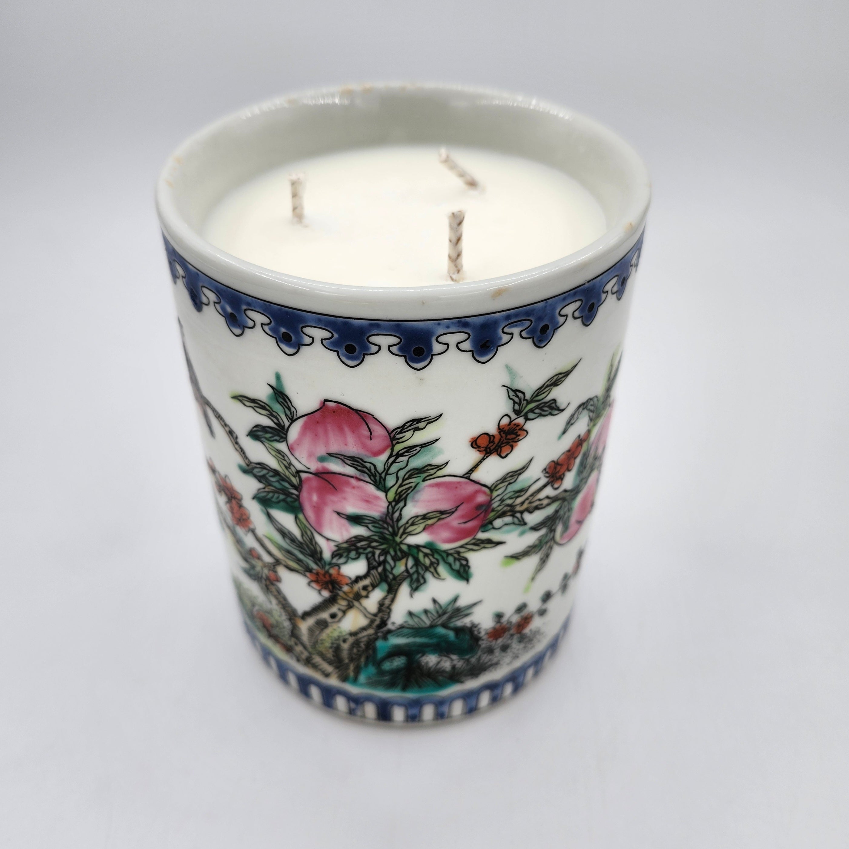 Peaches candle, peach-painted ceramic pot, three wicks, styled view