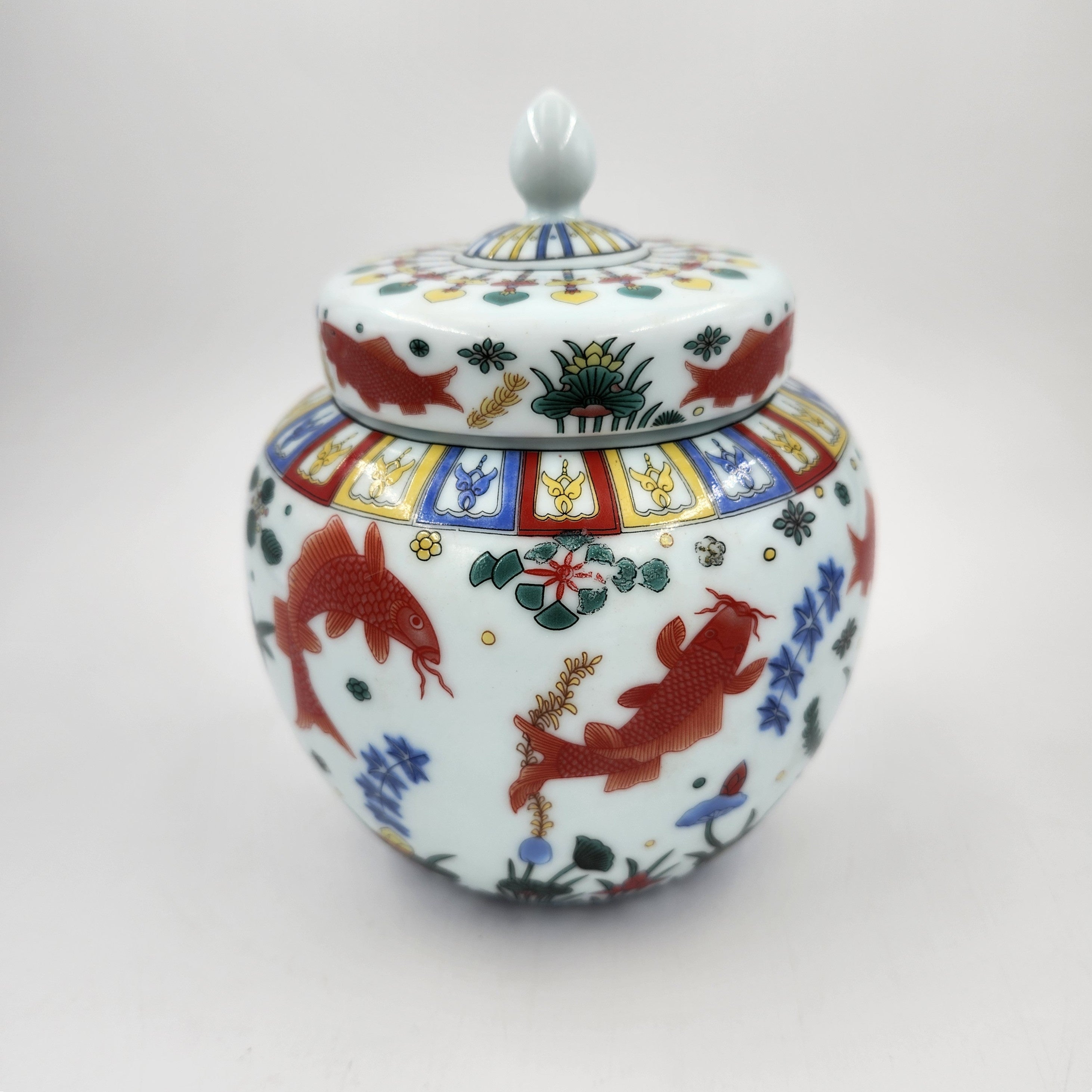 Scented candle in a decorative ceramic jar with golden koil colourful designs on a white background