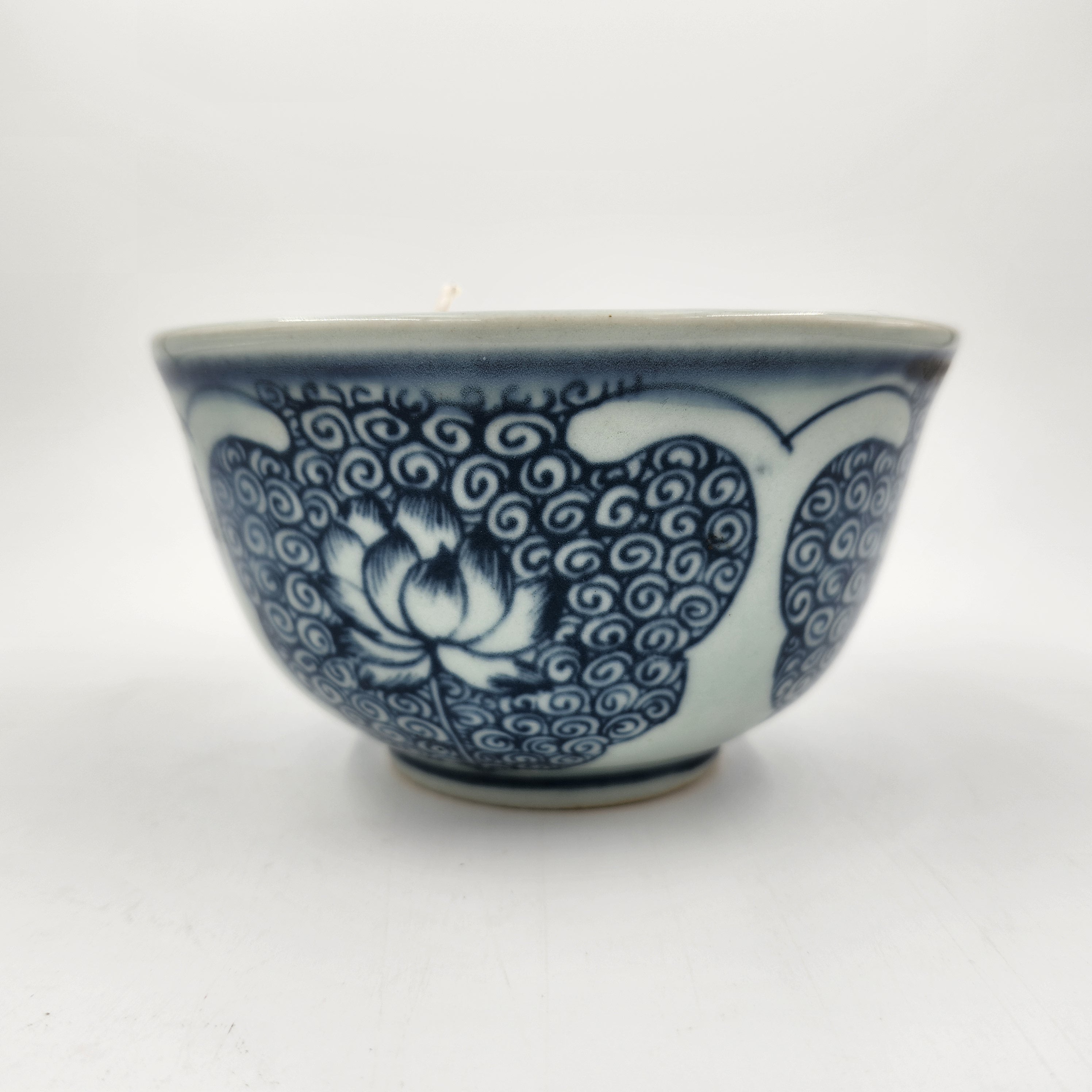 Blue and white ceramic rice bowl with lotus pattern on a white background
