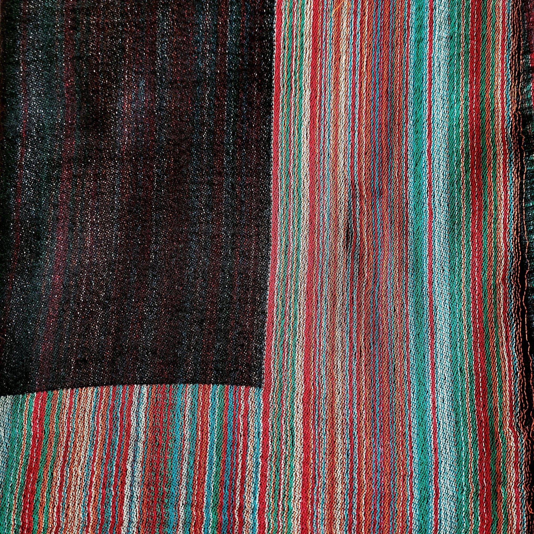 Multi striped pashmina silk shawl in charcoal, one side block colour with a multi striped border, reversed on the other