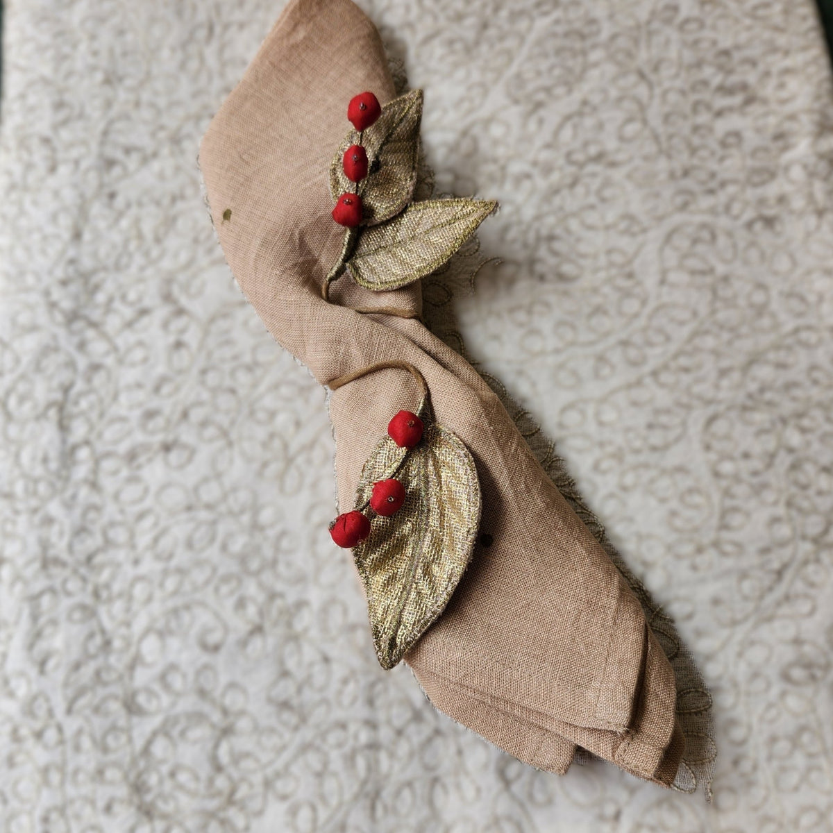 Detail of the red silk berries and stone grey velvet leaves on a Leaf napkin tie, gold on the underside, sold in sets of six