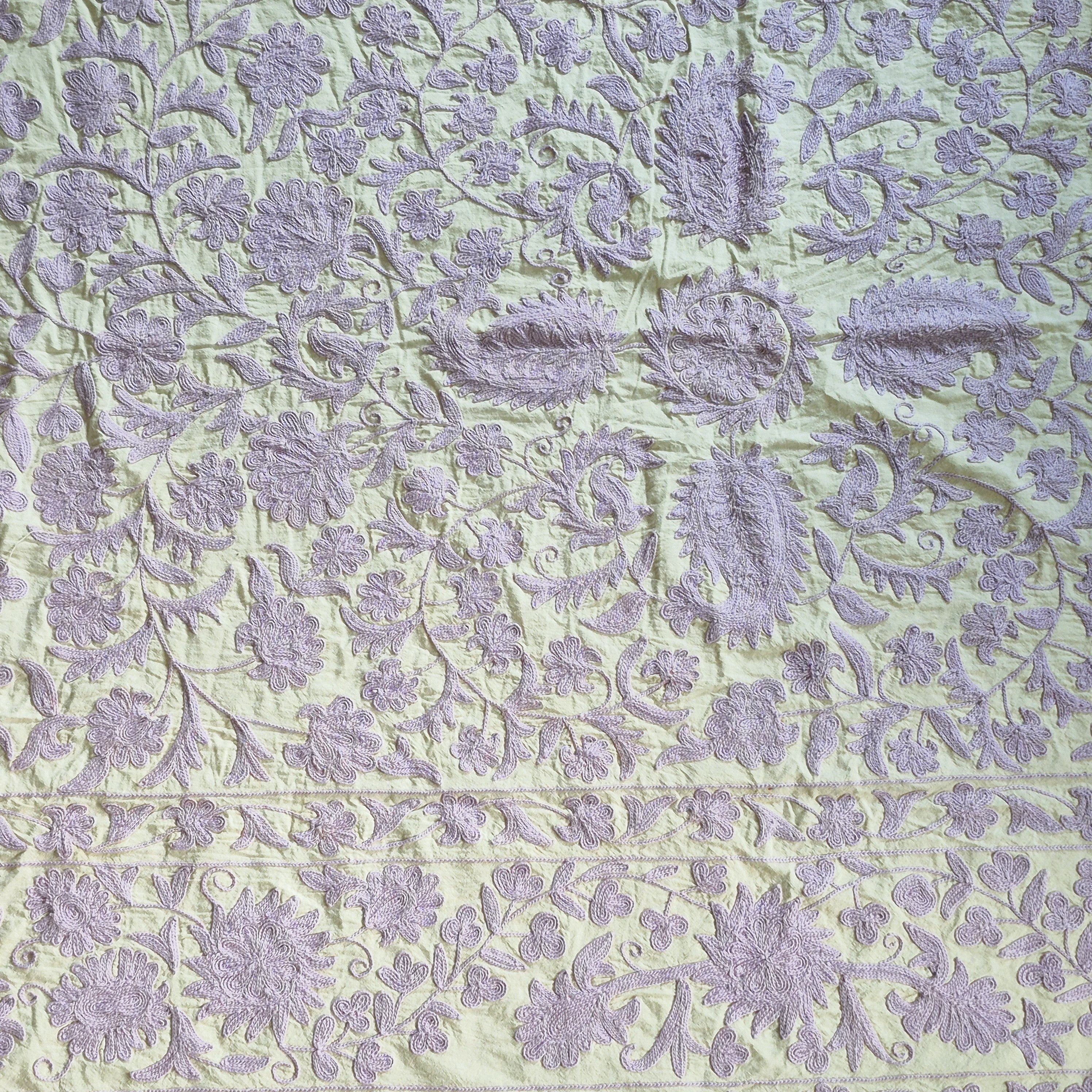 Suzani throw in lavender on pale green cotton, styled as a decorative wall hanging or draped sofa throw