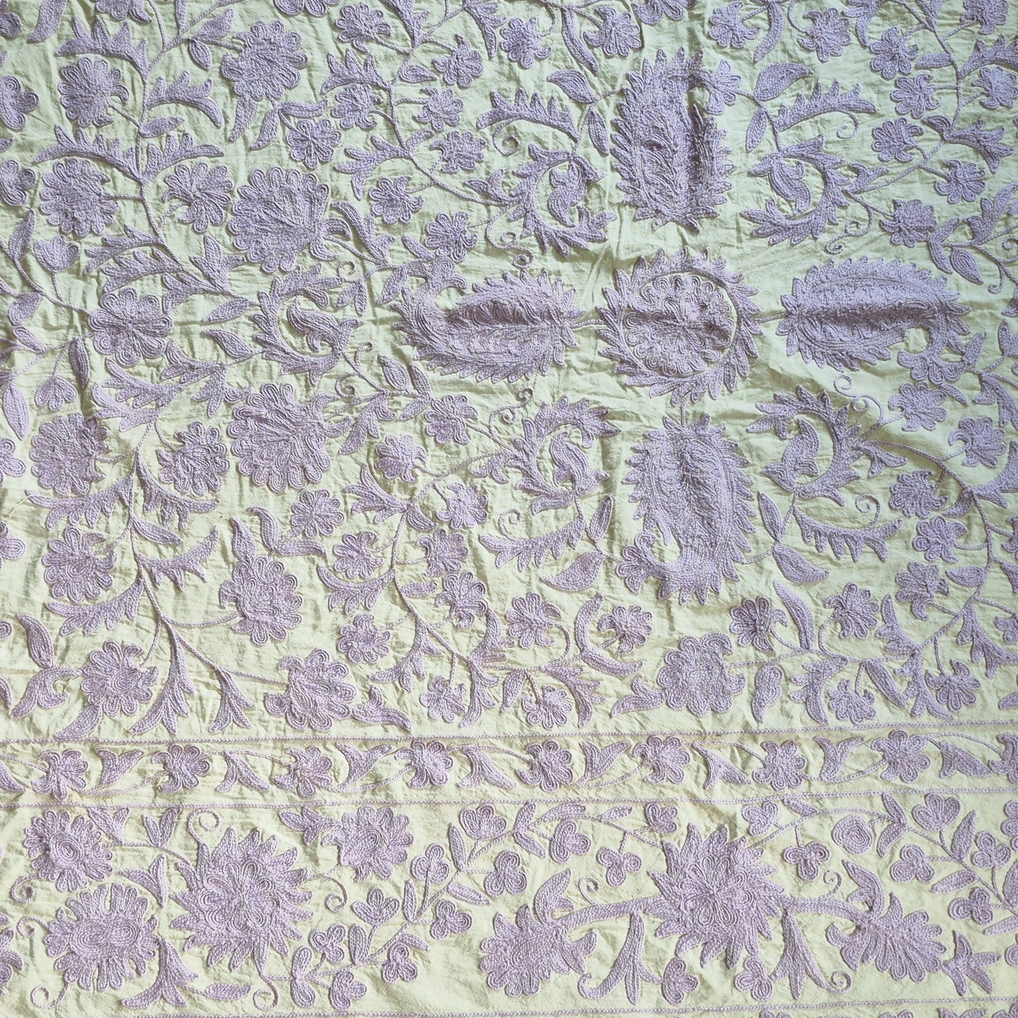 Suzani throw in lavender on pale green cotton, styled as a decorative wall hanging or draped sofa throw