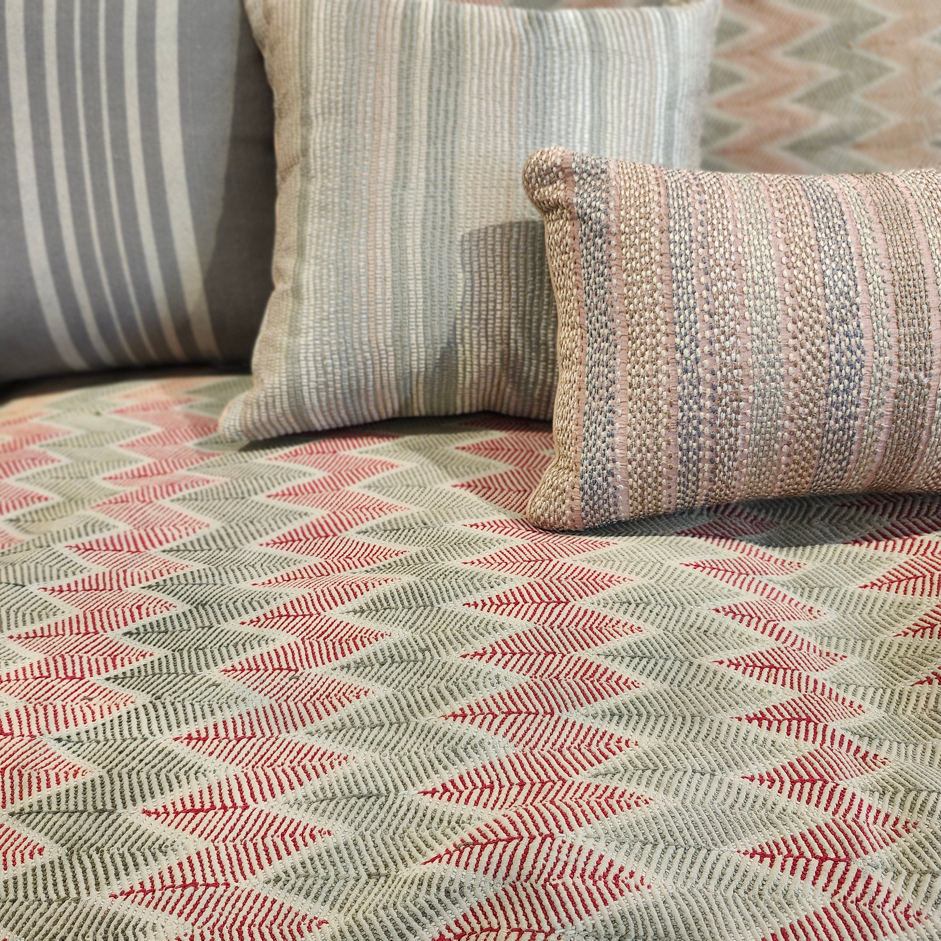 Hand embroidered cushion with shell pink stripes grouped with other cushions on a Zig Zag Vintage Kantha