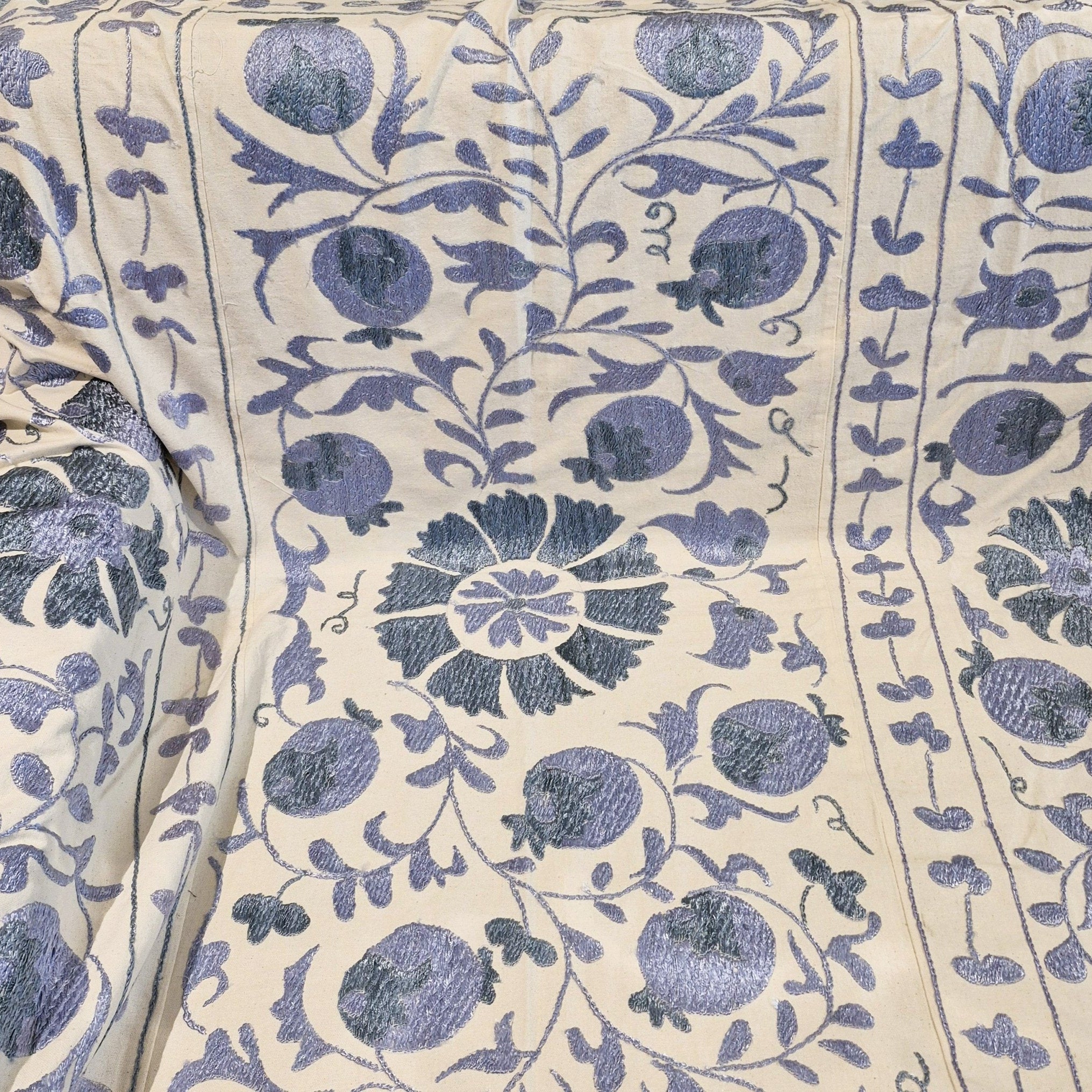 Suzani fabric with blue pomegranate pattern on cream background