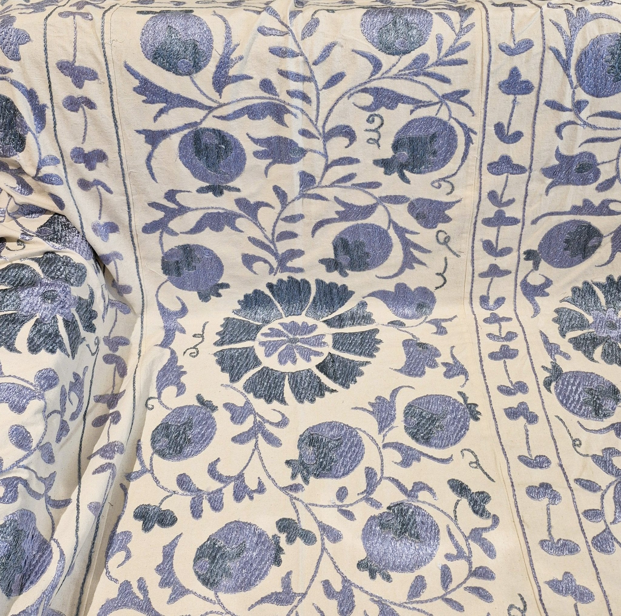 Suzani fabric with blue pomegranate pattern on cream background
