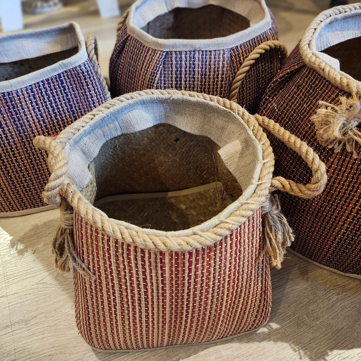 Set of lightweight handcrafted wicker laundry baskets with a dark stripe and rope handles, in several sizes