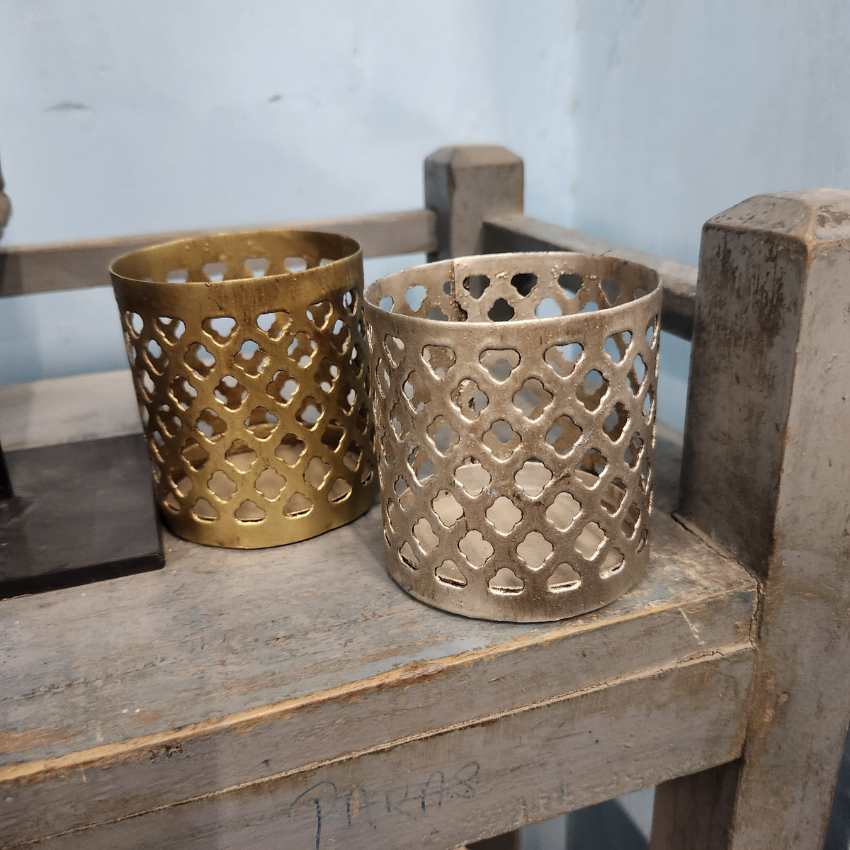 Iron tea light holders with fret-work sides, painted in silver and gold, 9cm high and 9cm in diameter.