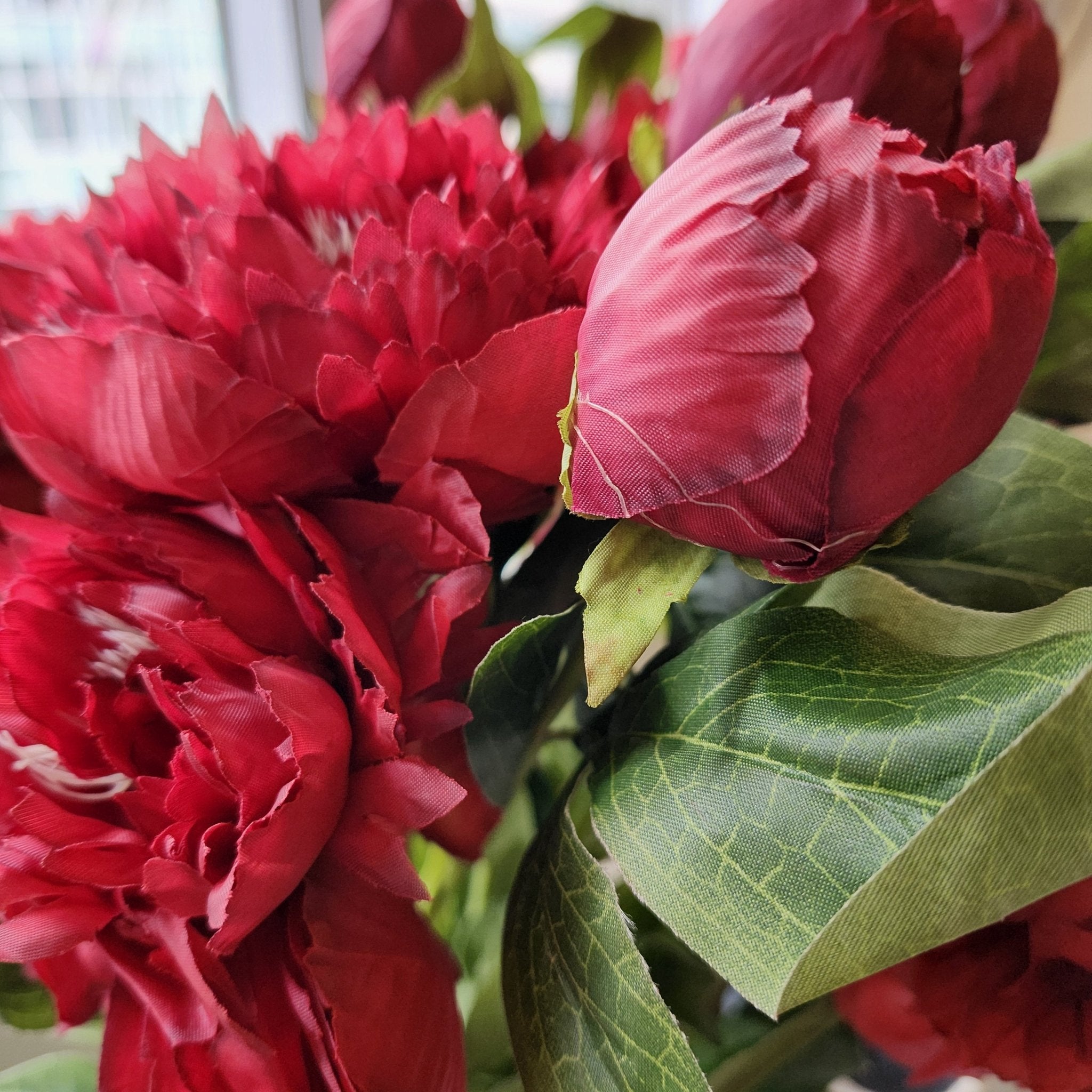 Vivid red artificial flower stem with two blooms and a bud