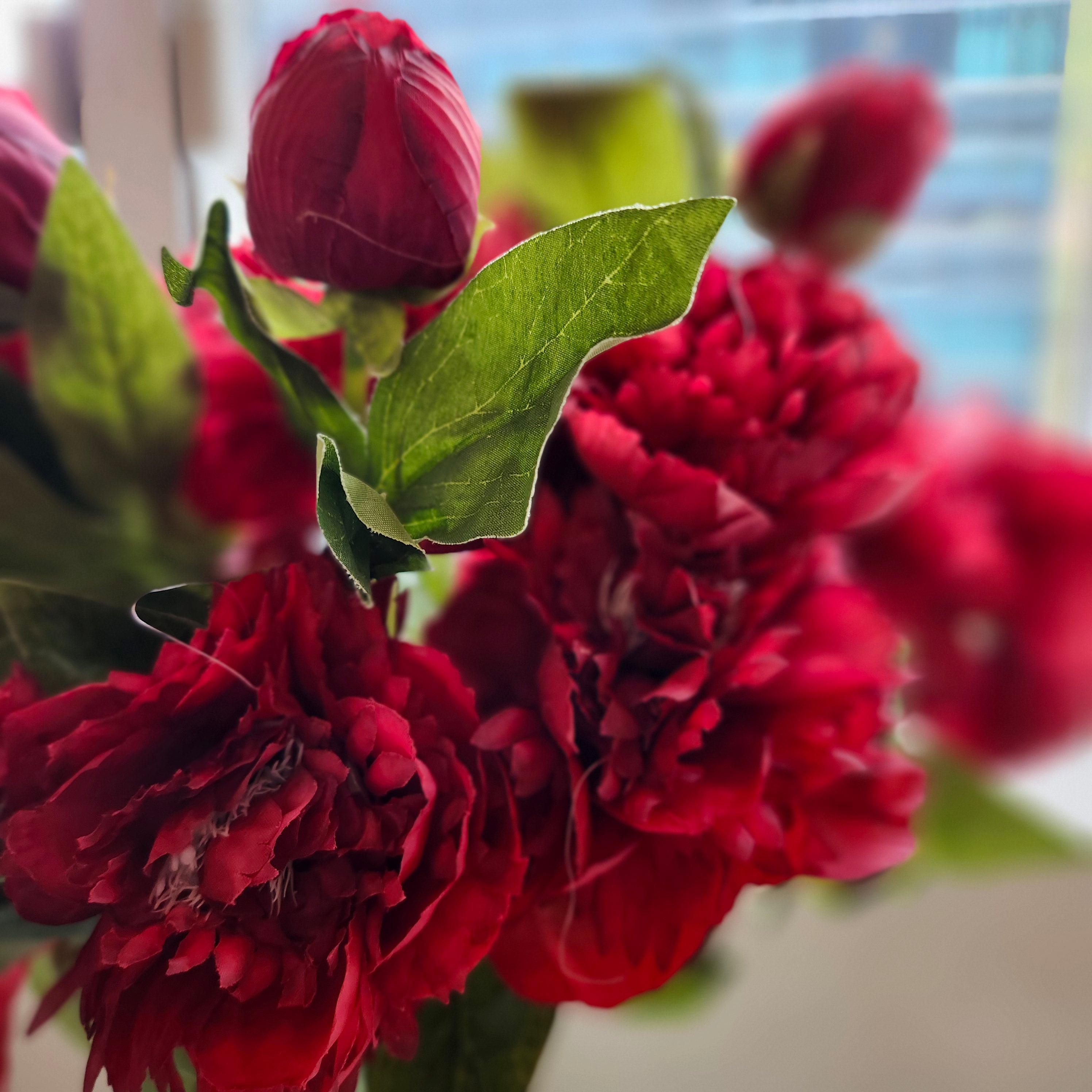 Red artificial flower with two blooms and a bud