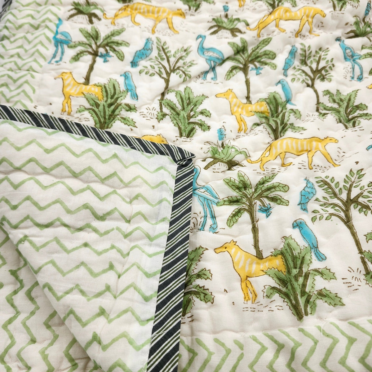 Child's jungle print quilt in organic cotton cambric, with yellow big cats and blue birds, 102 by 152cm, machine washable