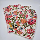 Short pyjamas with a vibrant hand-block print featuring pink flowers, red and orange pomegranates, and green leaves on a cream background.
