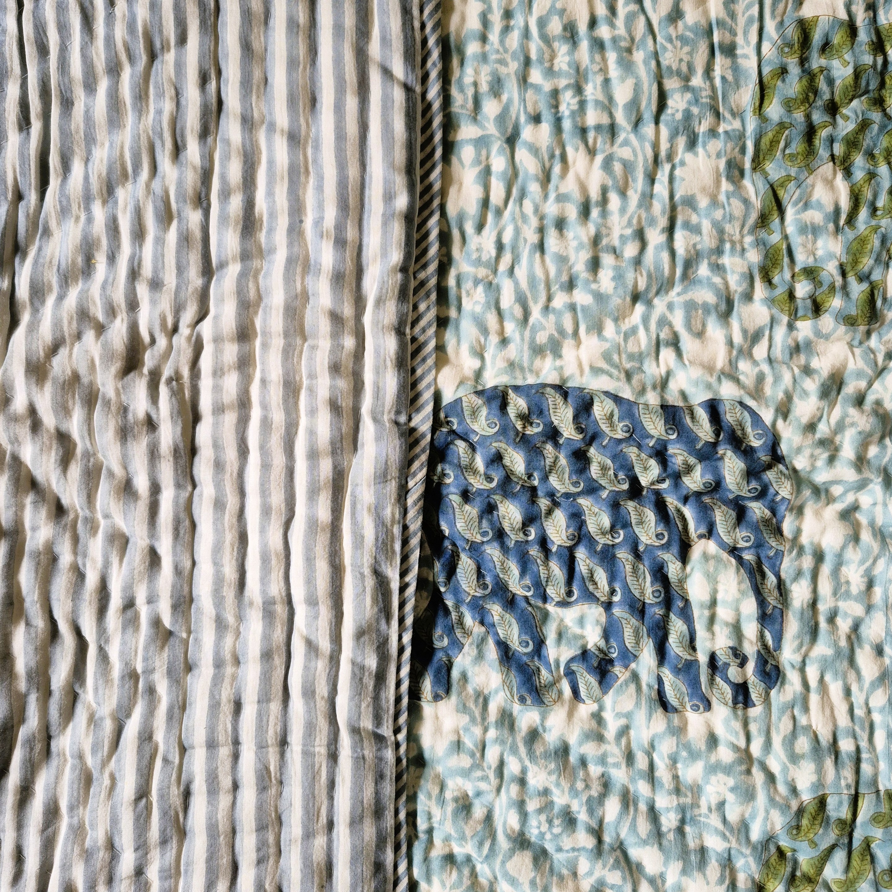 Toddler block-print quilt with blue and green elephants and a striped reverse