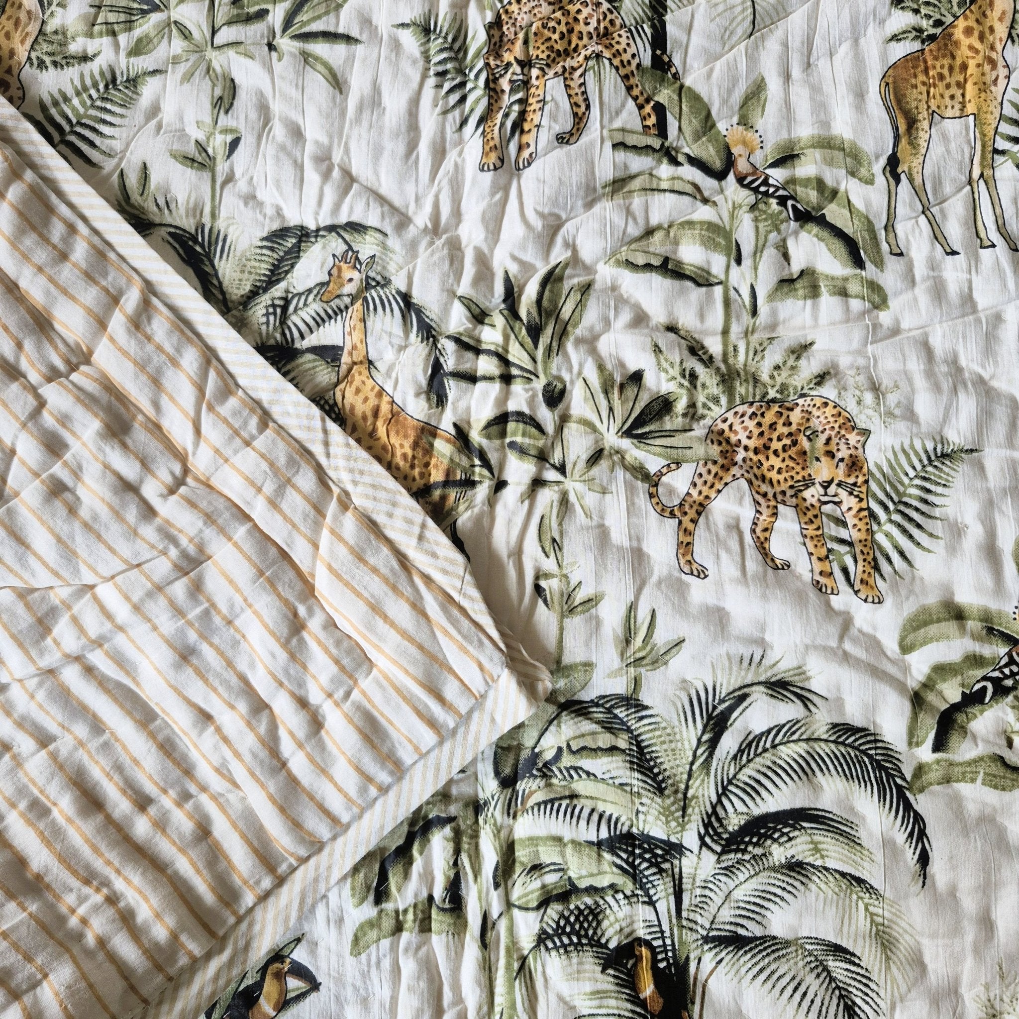 Toddler block-print cotton quilt with a jungle print of giraffes, leopards and hoopoes, made in India