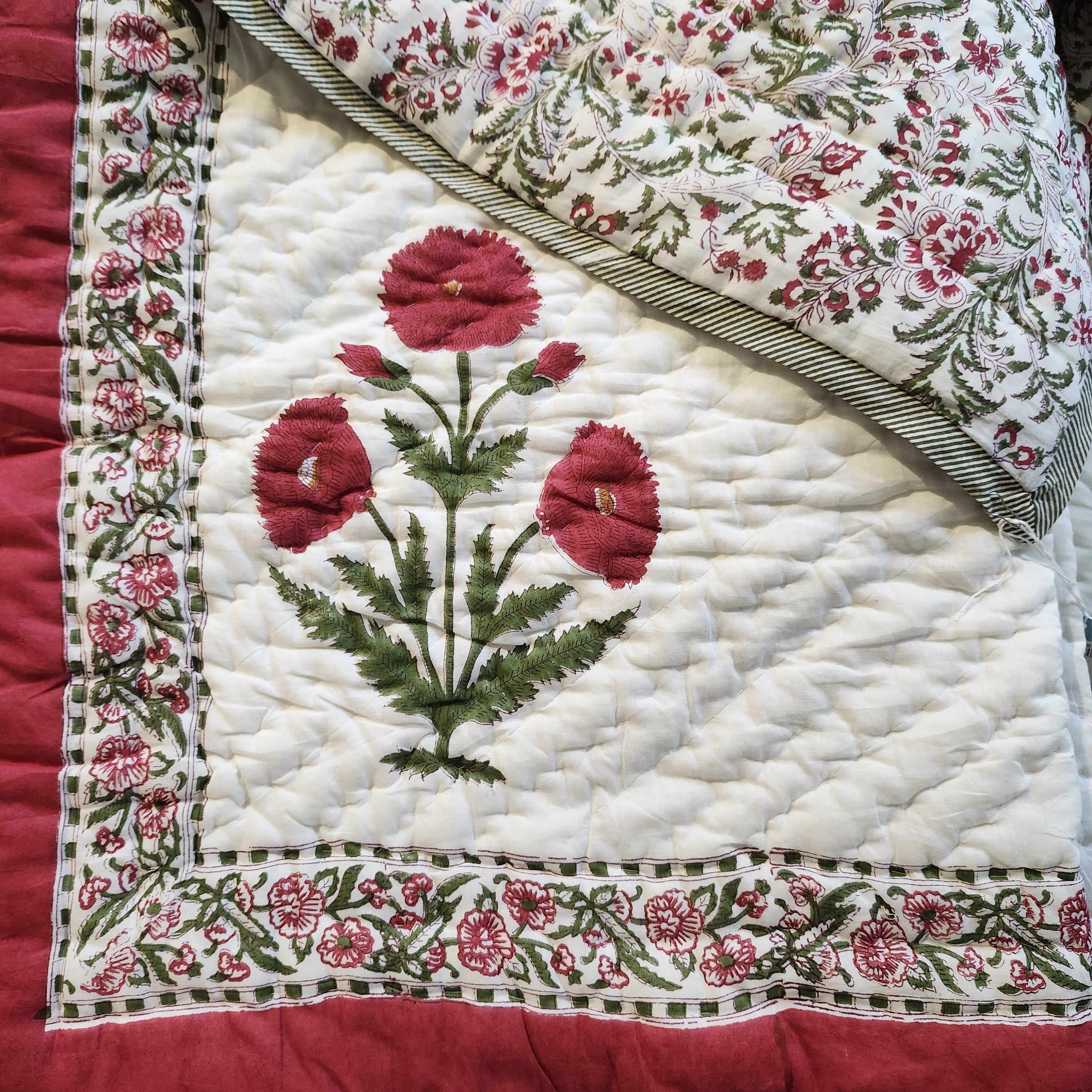 Single block-print quilt with poppies and a floral border in red and green