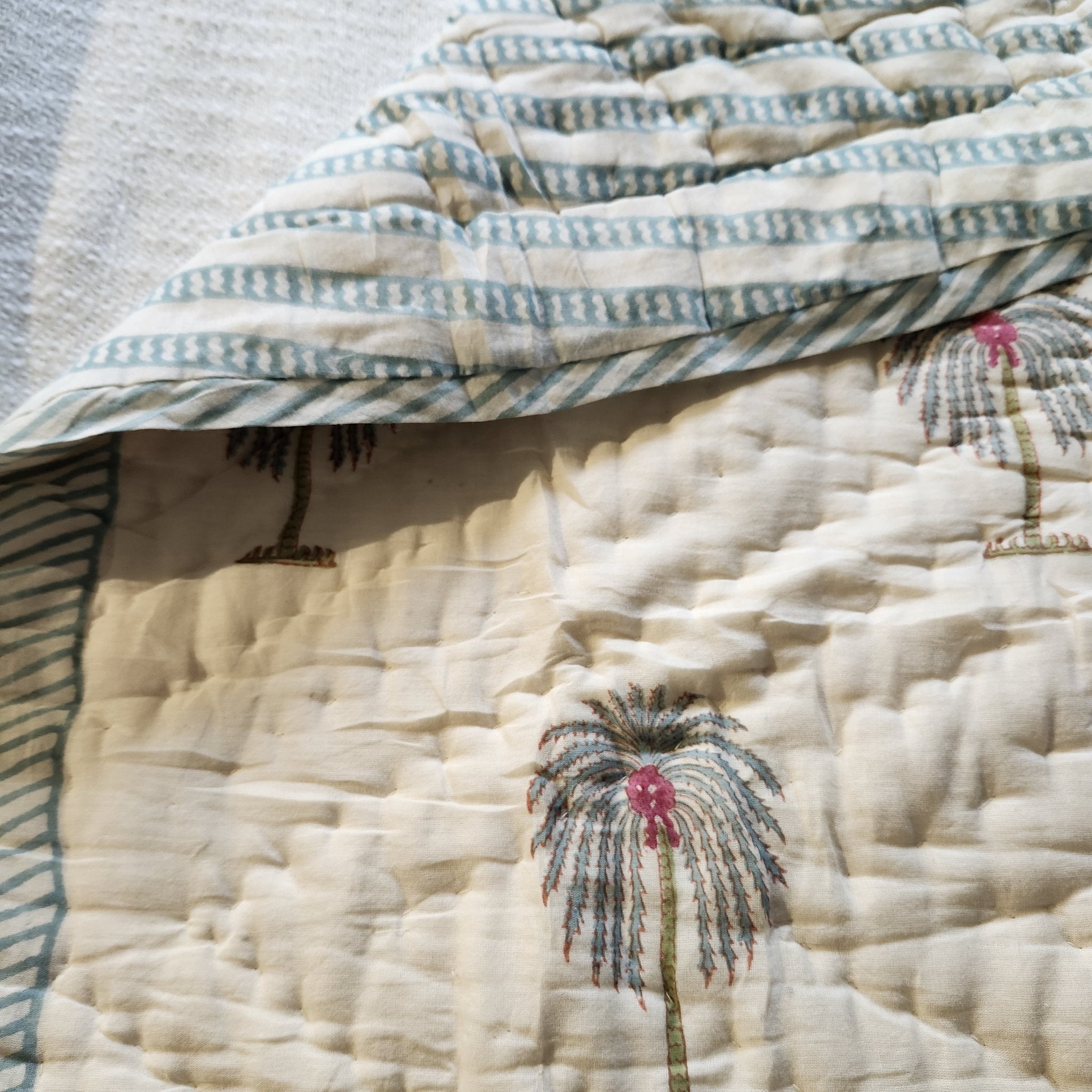 Children's block-print cotton quilt with a pattern and contrast striped reverse