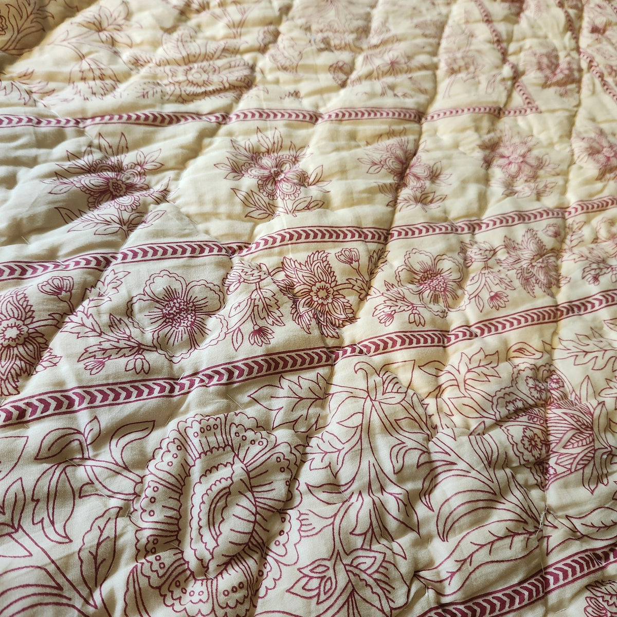 Detail of the beige Mughal floral block print on a soft, lightweight and reversible queen size cotton quilt, made in India