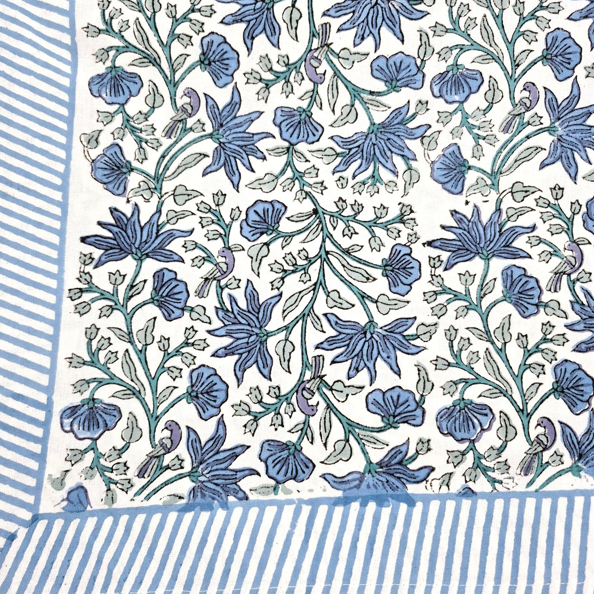 Floral block print tablecloth with blue flowers, green leaves and little birds on a white background