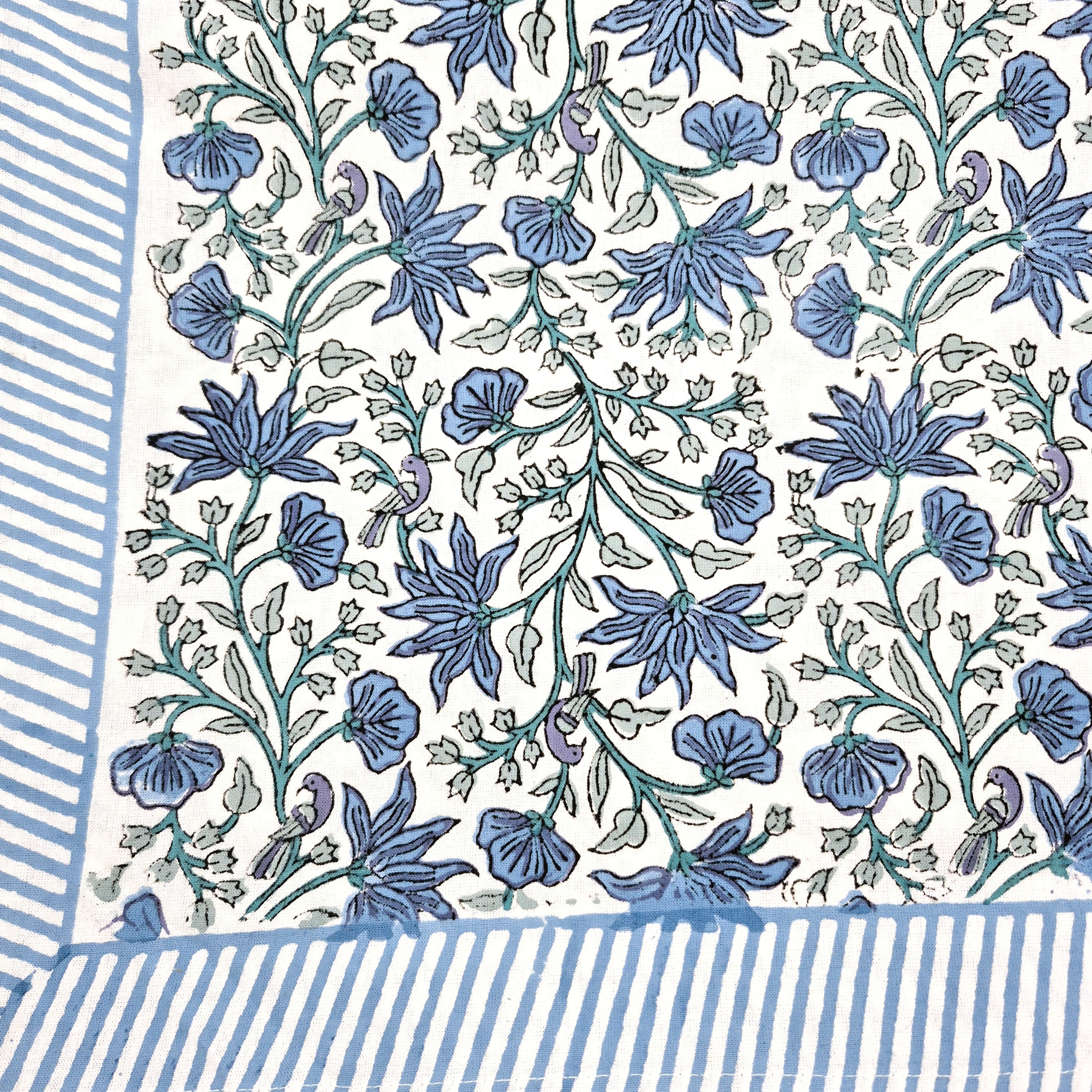 Floral block print tablecloth with blue flowers, green leaves and little birds on a white background