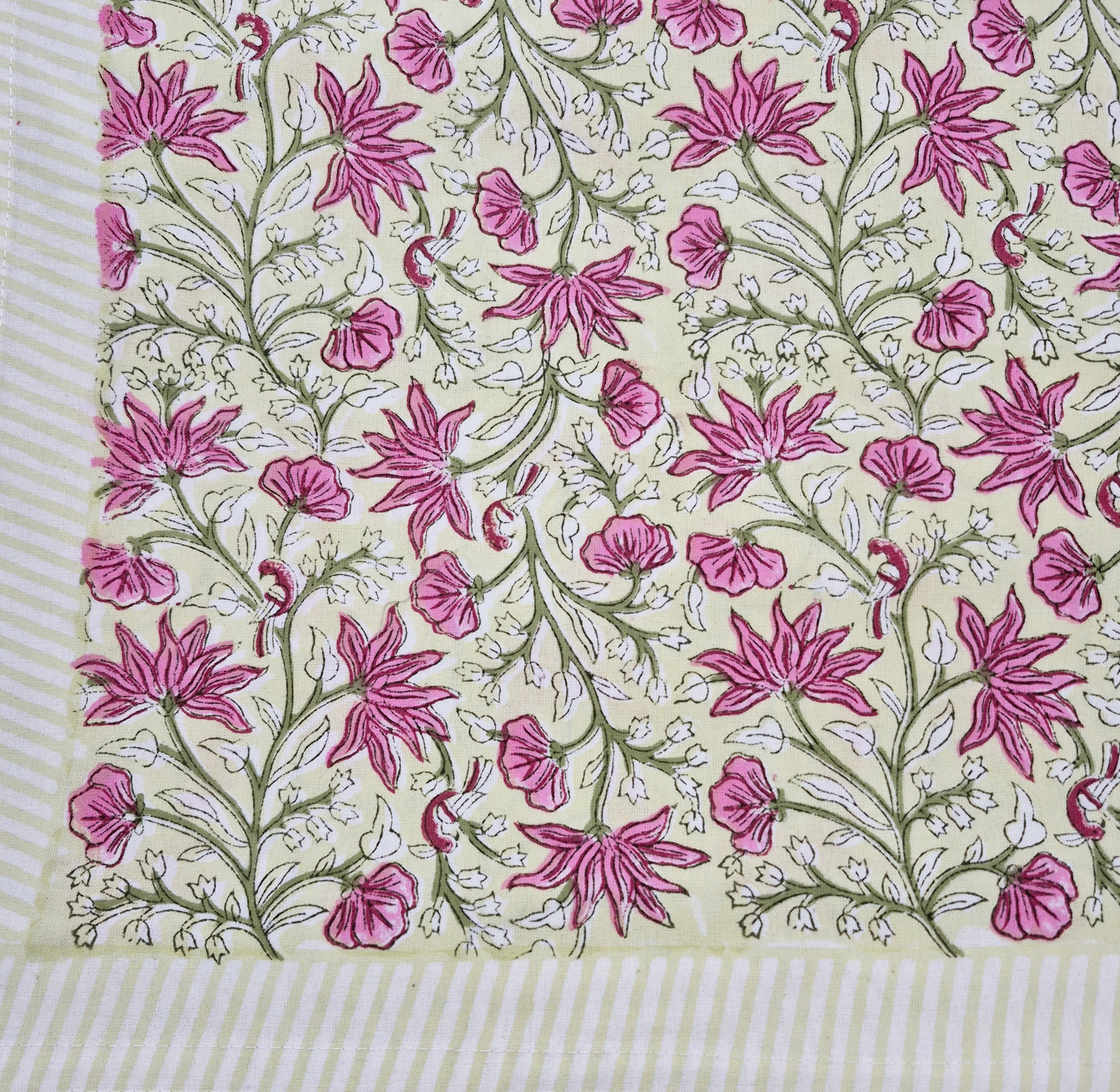 Floral block print table cloth with pink flowers, green leaves and tiny birds on a yellow background