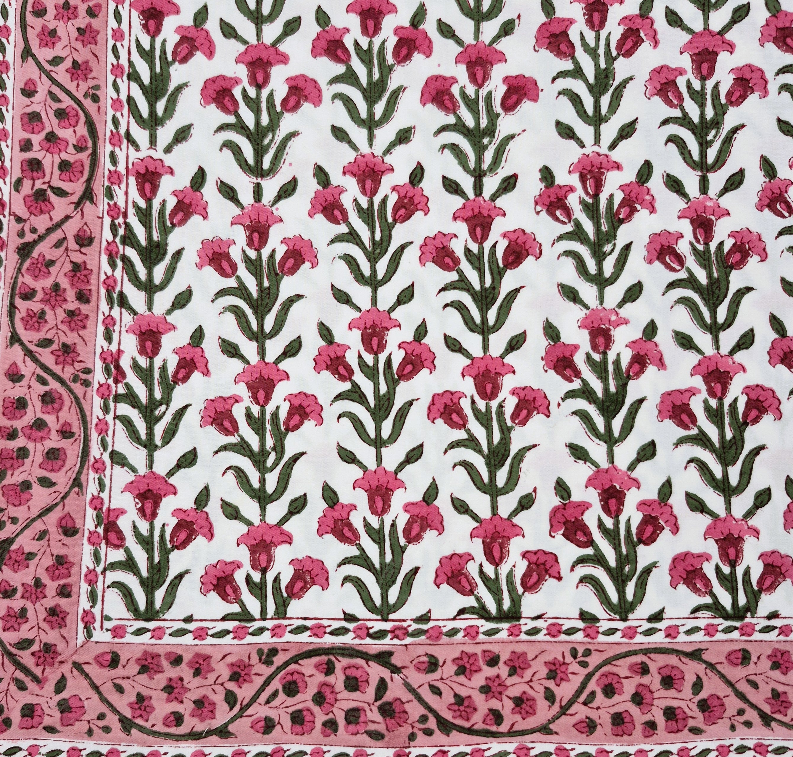 Floral patterned block print tablecloth with pink flowers and green leaves on a white background.