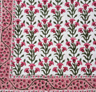 Floral patterned block print tablecloth with pink flowers and green leaves on a white background.