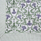 Block print tablecloth with violet flowers and green leaves on a white background
