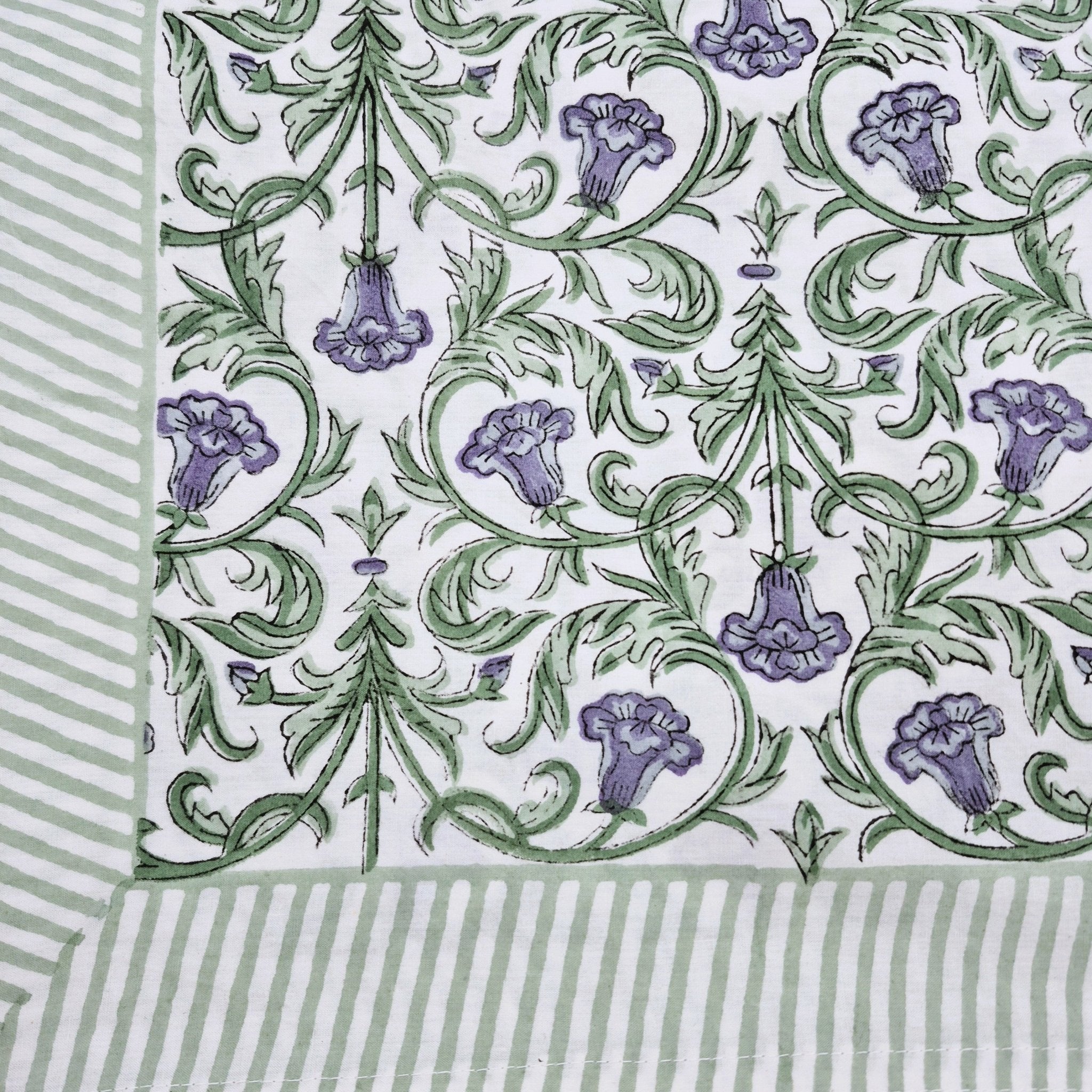 Block print tablecloth with violet flowers and green leaves on a white background