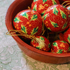 Red papier-mache Christmas bauble hand-painted with holly leaves and berries