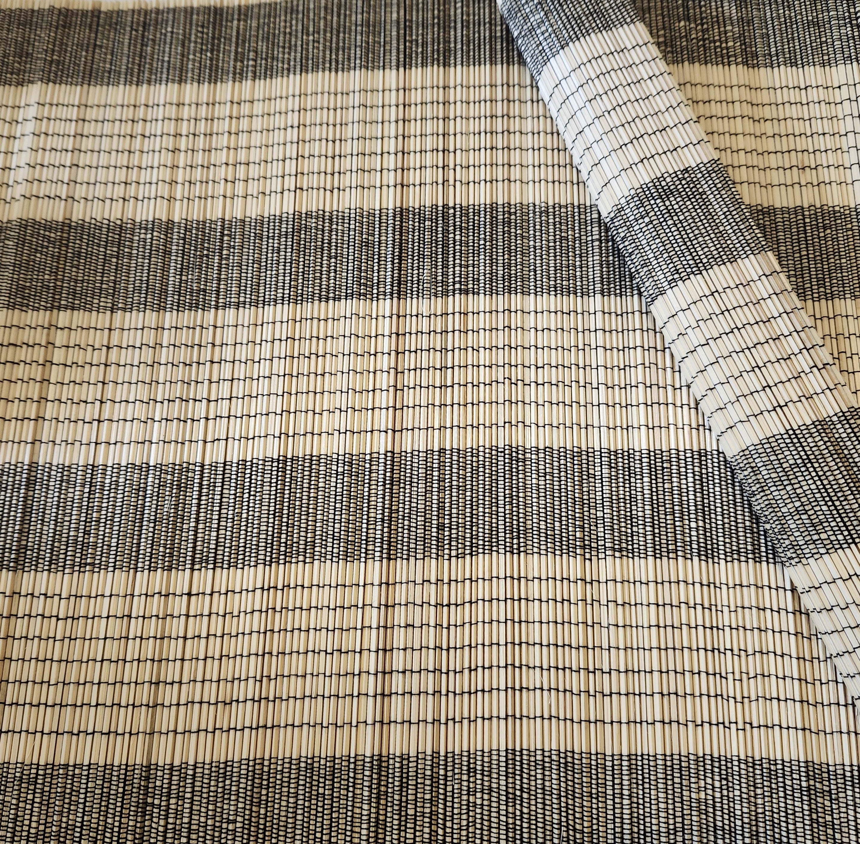 A natural bamboo placemat or table mat with black thread