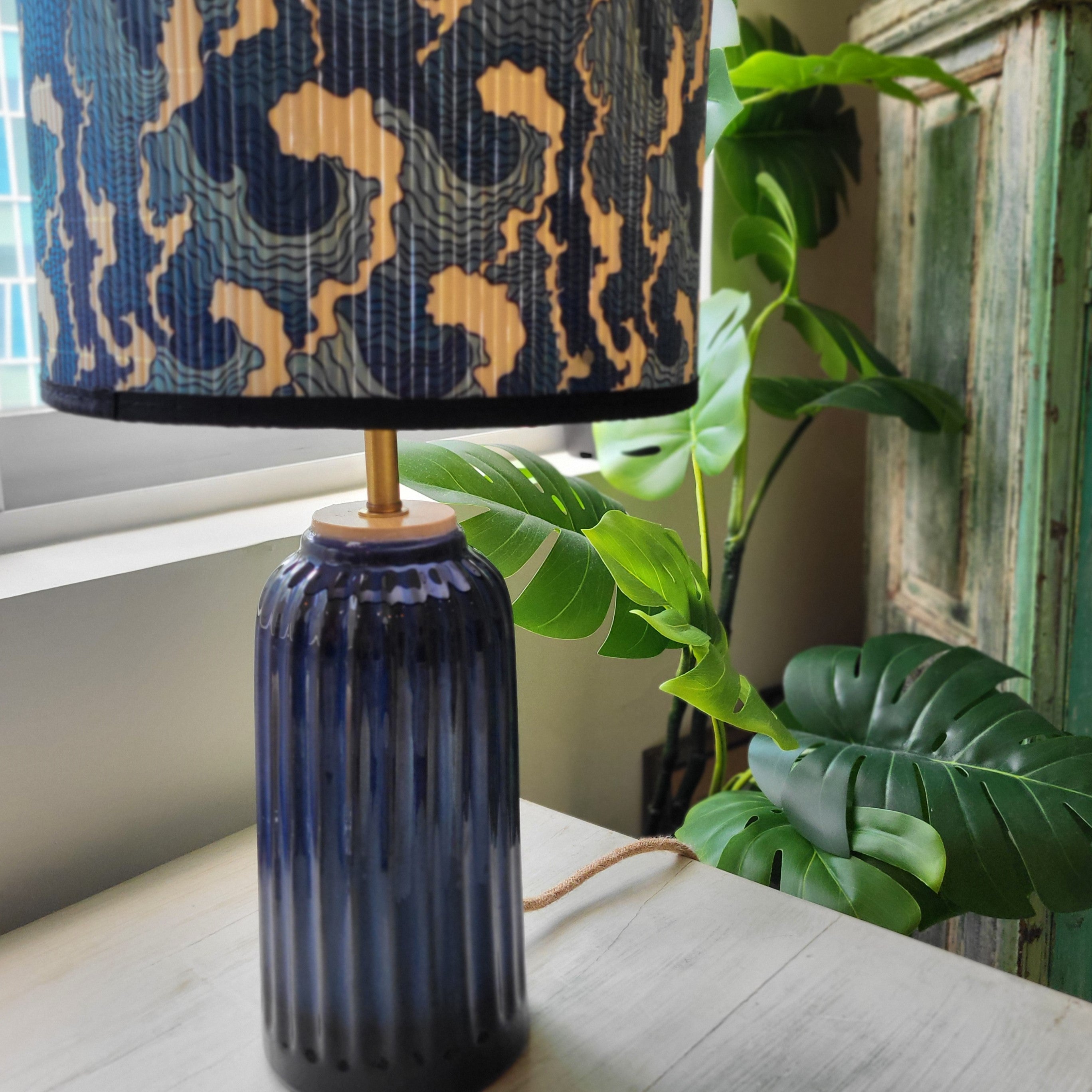 Bamboo-shade table lamp with a hand-painted tropical design on a teal base