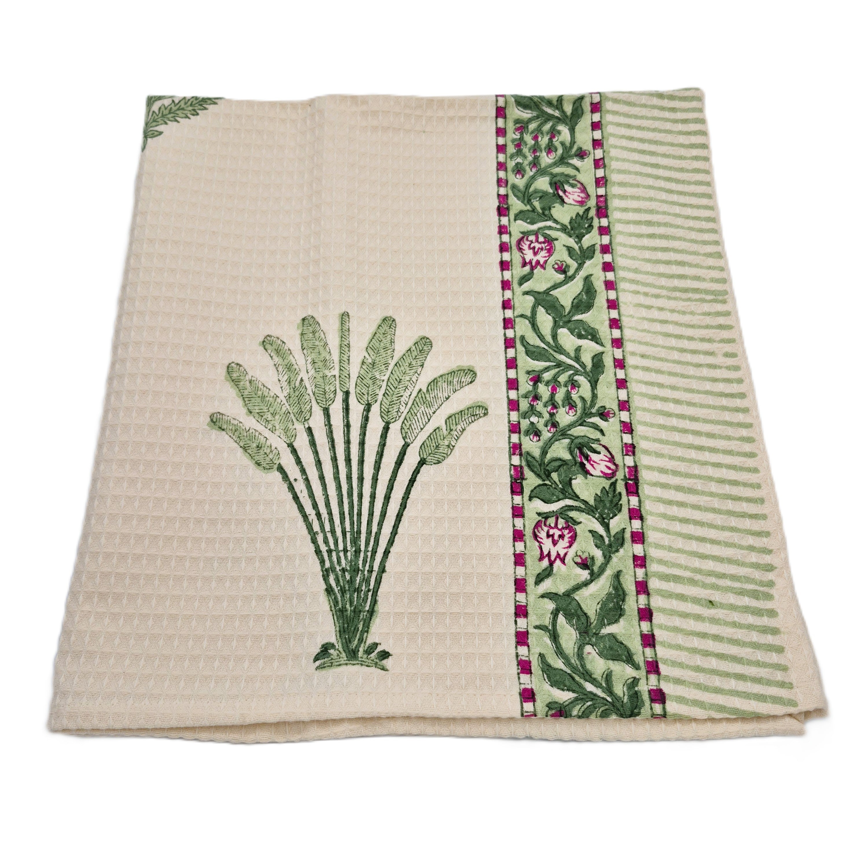 Cream waffle towel with a palm design and floral border on a white background